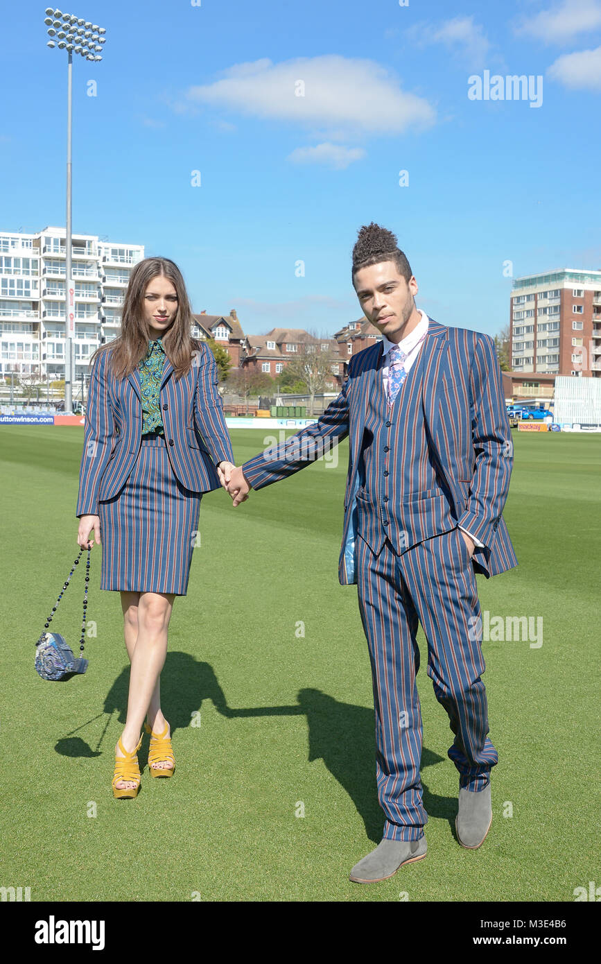 Ein schönes Mädchen mit einem Maßanzug und einen stattlichen gemischten Rennen Kerl in einem Anzug zu Fuß aroungd ein Cricket Ground an einem hellen Tag Stockfoto