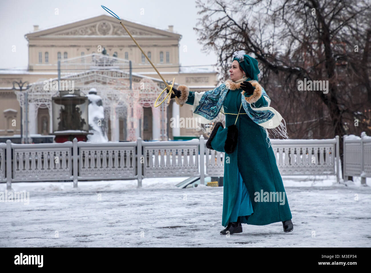 Eine Dame im historischen Kleid spielt das Spiel Serso auf dem Platz der Revolution auf dem Hintergrund des Bolschoi Theater in Moskau, Russland Stockfoto