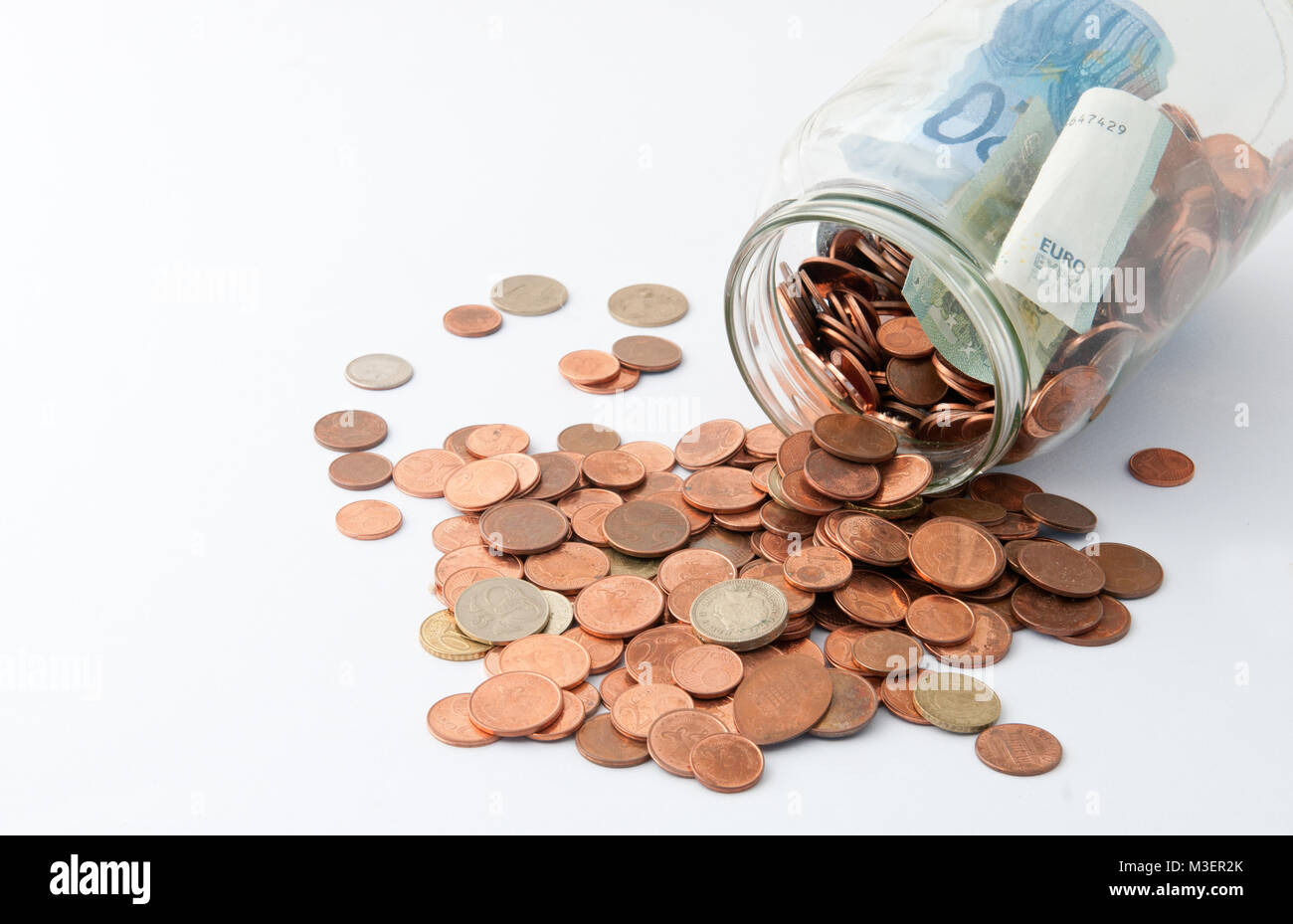 Glas voll von Euro-Münzen und -Banknoten isoliert auf Weiss. Konzept für Einsparungen, Tipps und Spenden. Stockfoto
