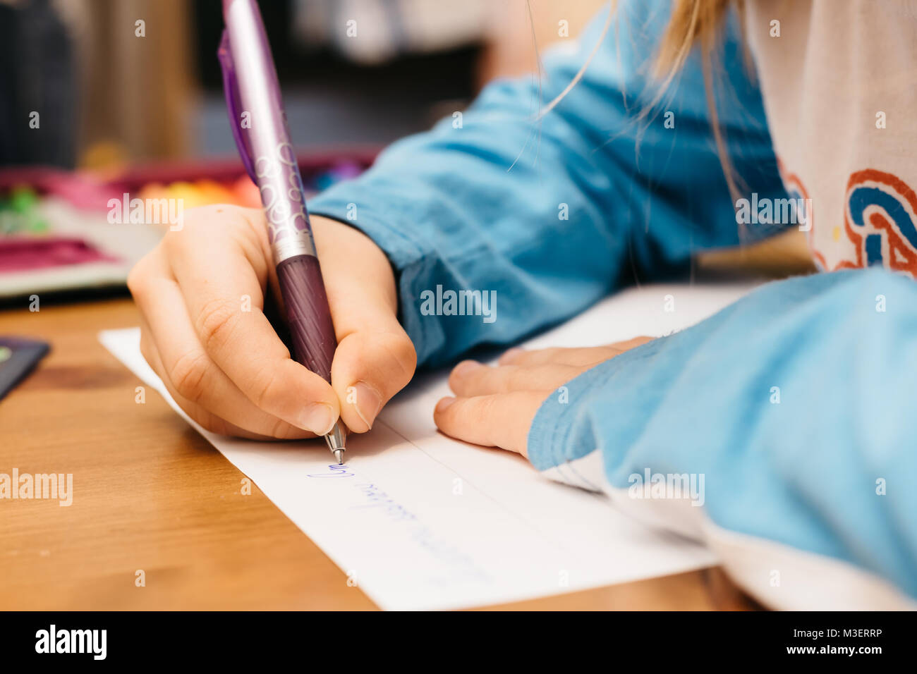 Kind Hausaufgaben machen. Ein junges Mädchen schreibt auf Papier und einen Stift. Stockfoto