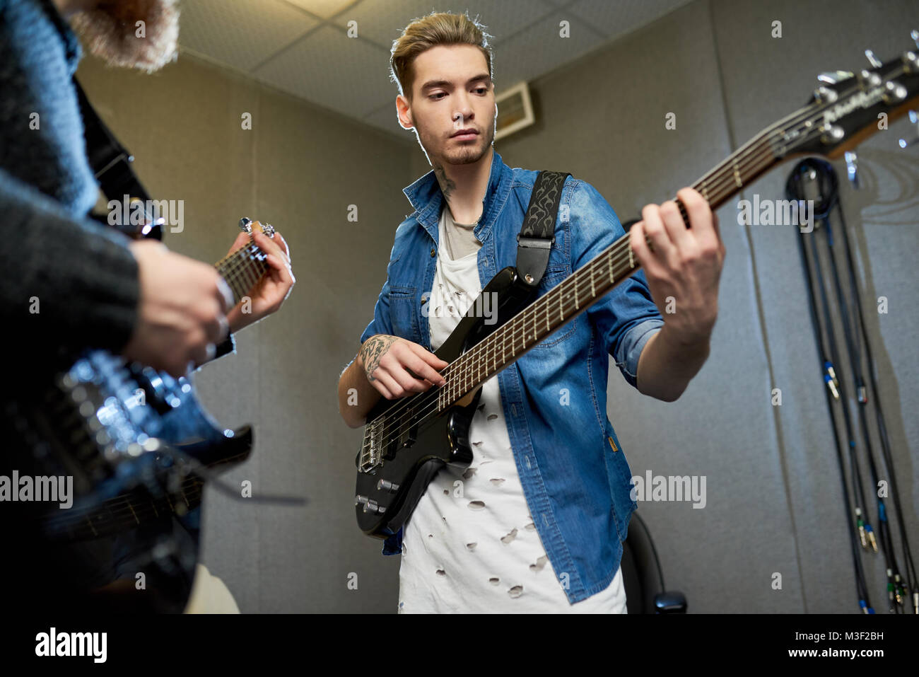 Konzentrierte Musiker Gitarre spielen mit Mentor im Studio Stockfoto