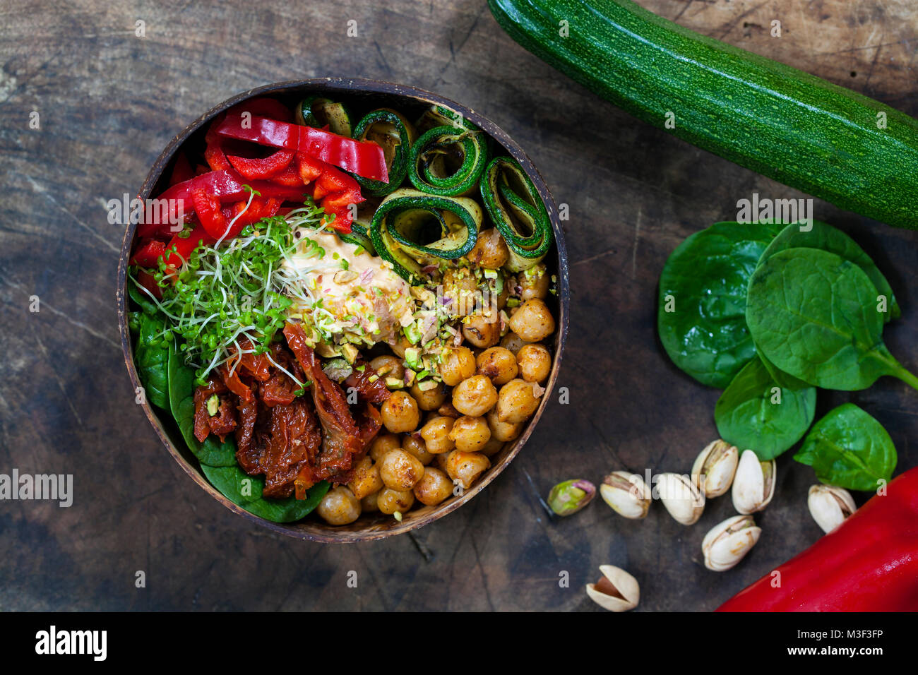 Vegan Schüssel mit würzige Kichererbsen, Zucchini, Paprika und Hummus