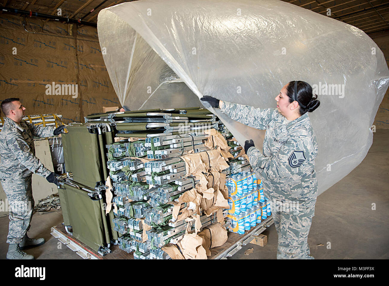 Master Sgt. Angie Hall, 434Th Squadron bekämpfung Logistik Bereitschaft Bereitschaft, Techniker und Master Sgt. Adam Oswalt, 434Th LRS Training Manager, Plastikfolien auf der Oberseite des Cargo an Grissom Air Reserve Base, Ind., Sept. 11, 2017. Die Palette der Ladung wird zum Versand zu Florida als Teil des Hurrikans Irma Hilfsmaßnahmen vorbereitet. (U.S. Air Force Stockfoto