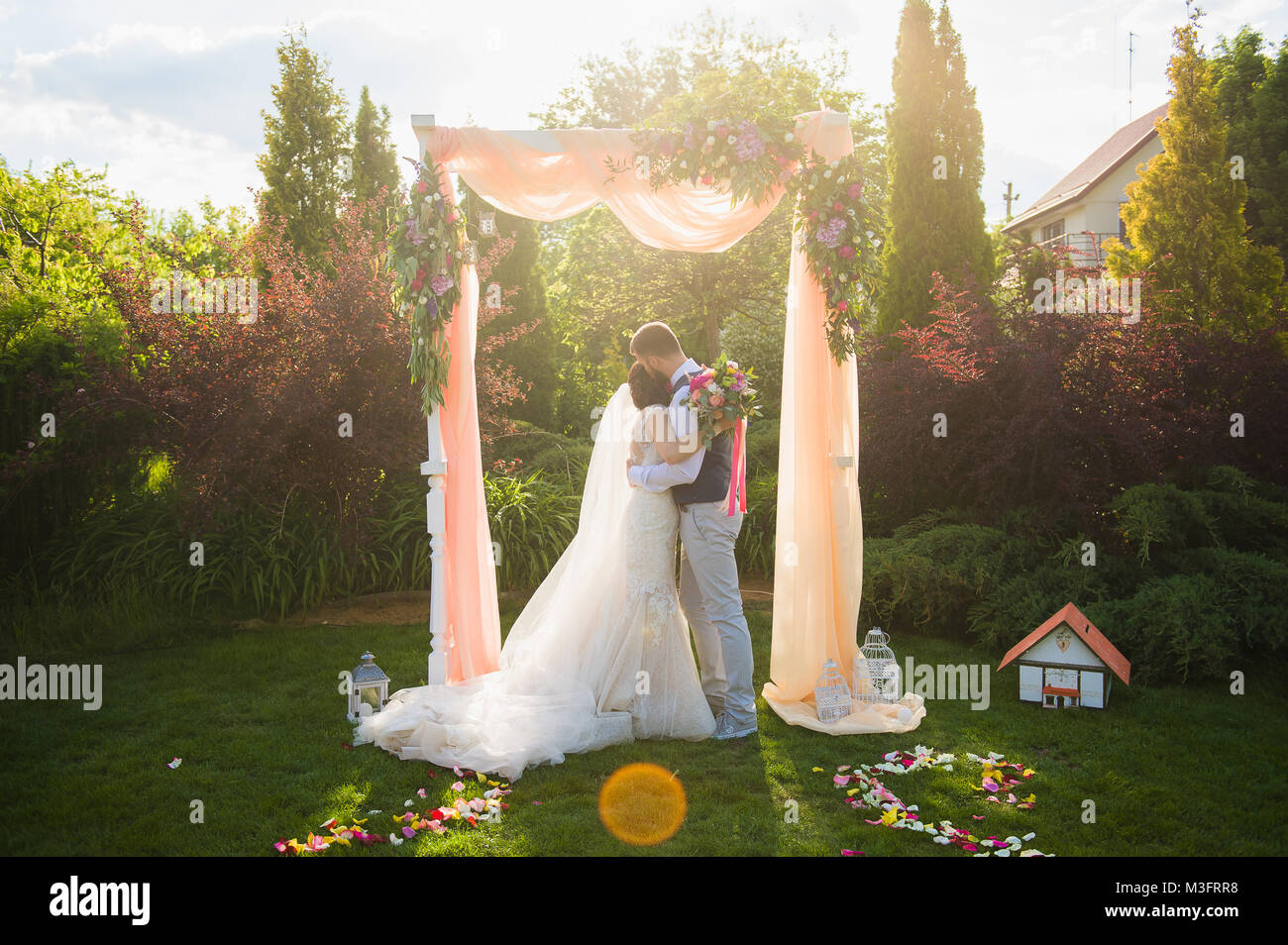 Braut und Bräutigam einander Holding unter dem Bogen am Garten Stockfoto