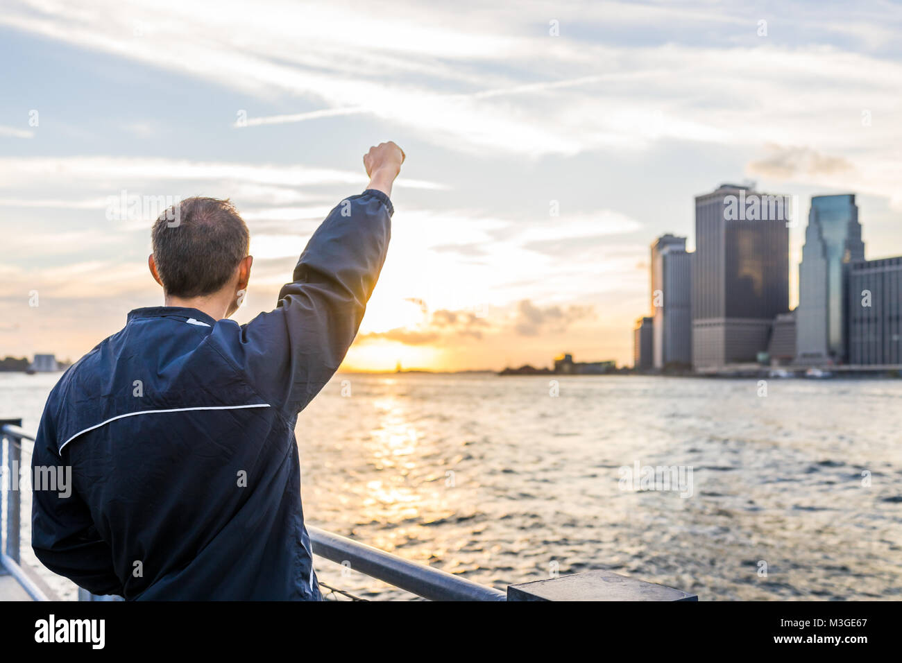 Zurück junger Mann draußen im Freien in NYC New York City Brooklyn Bridge Park am East River, Geländer, Blick auf Skyline Skyline Sonnenuntergang, Stat Stockfoto