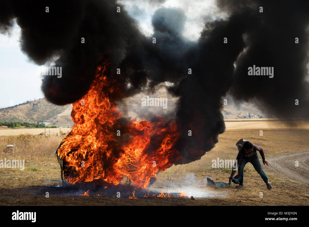 Brennende Reifen dichten schwarzen toxischen Rauch Spalten wirbelnden Feuer flammen Stockfoto