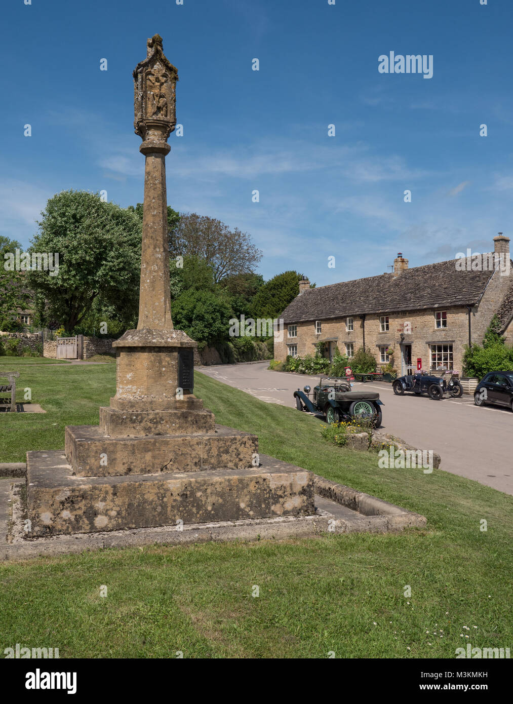 Die Alte Post und Kriegerdenkmal an guiting Macht in den englischen Cotswolds zusammen mit zwei klassischen Autos in der Nähe geparkt. England. UK. Stockfoto