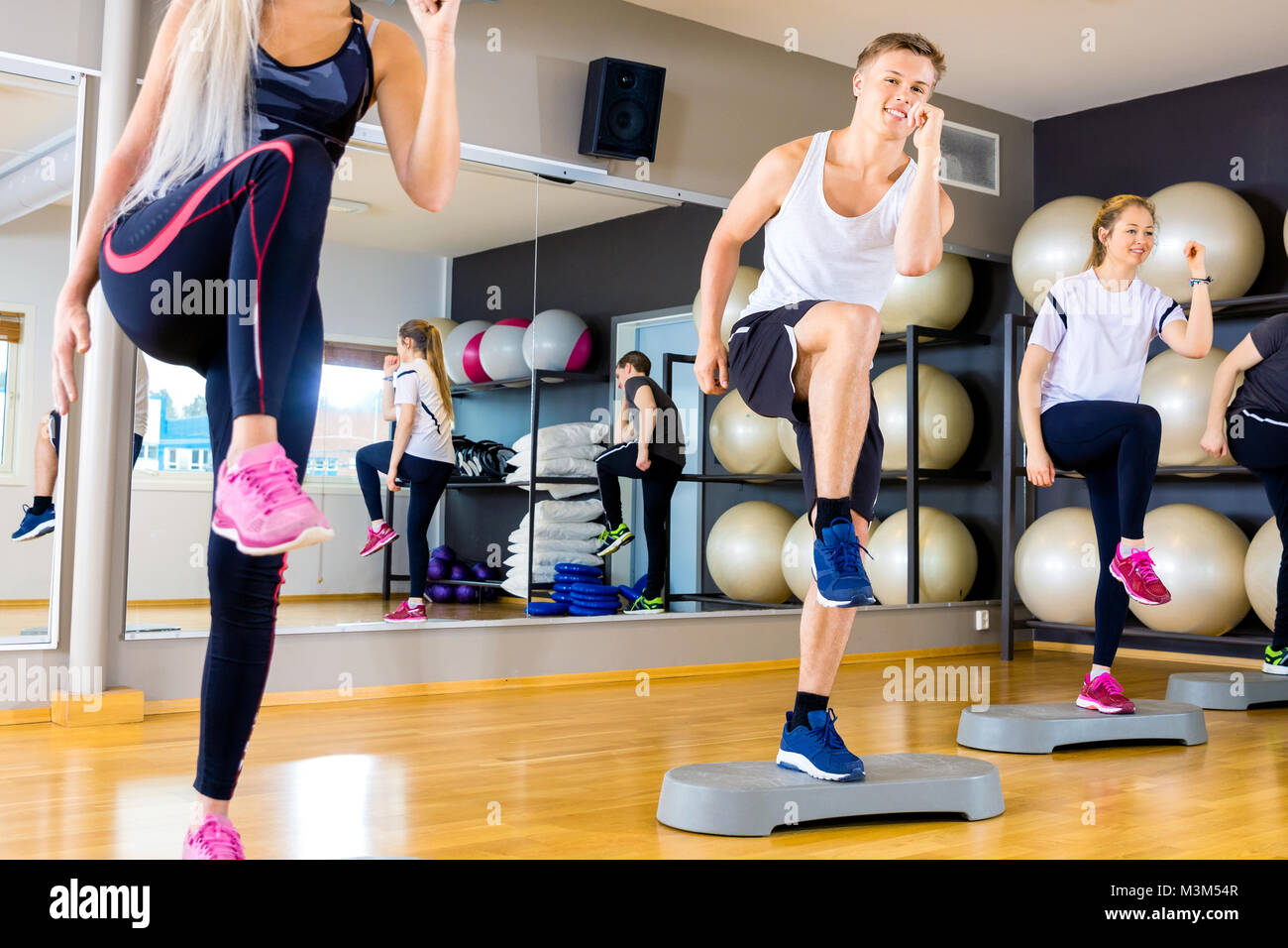 Lächelnde Gruppe Anheben der Beine auf Schritt-Plattformen im Fitness-Studio Stockfoto