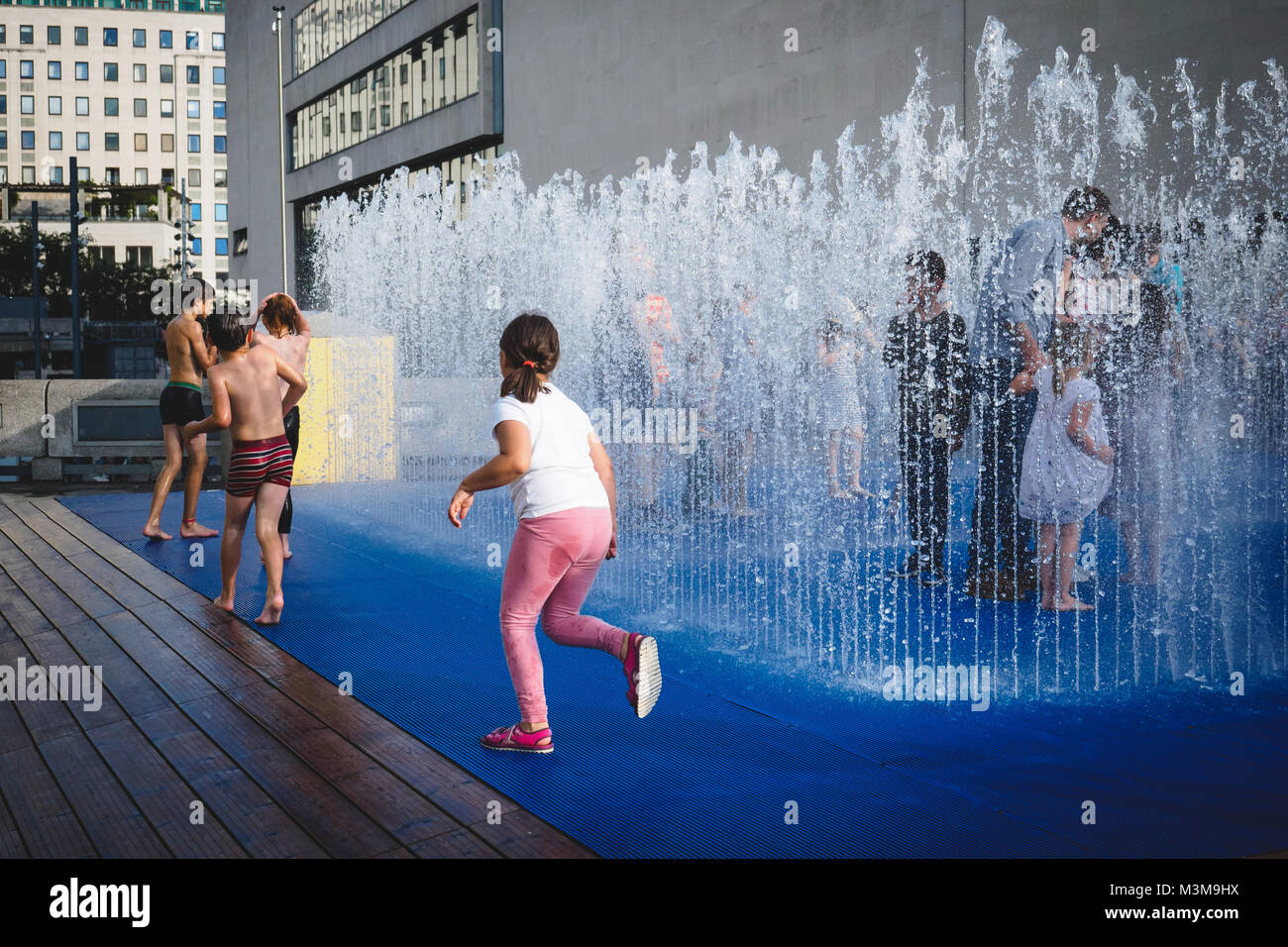 London (UK), August 2017. Familie mit Kindern und Kinder spielen in einem Brunnen in der Nähe der Royal Festival Hall im South Bank. Querformat. Stockfoto