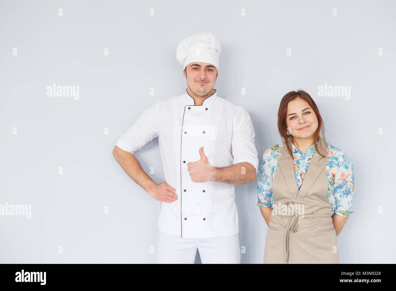 Koch Männer und Frau mit Schürze auf hellen Hintergrund isoliert. Paar bei der Arbeit. Daumen hoch. Stockfoto