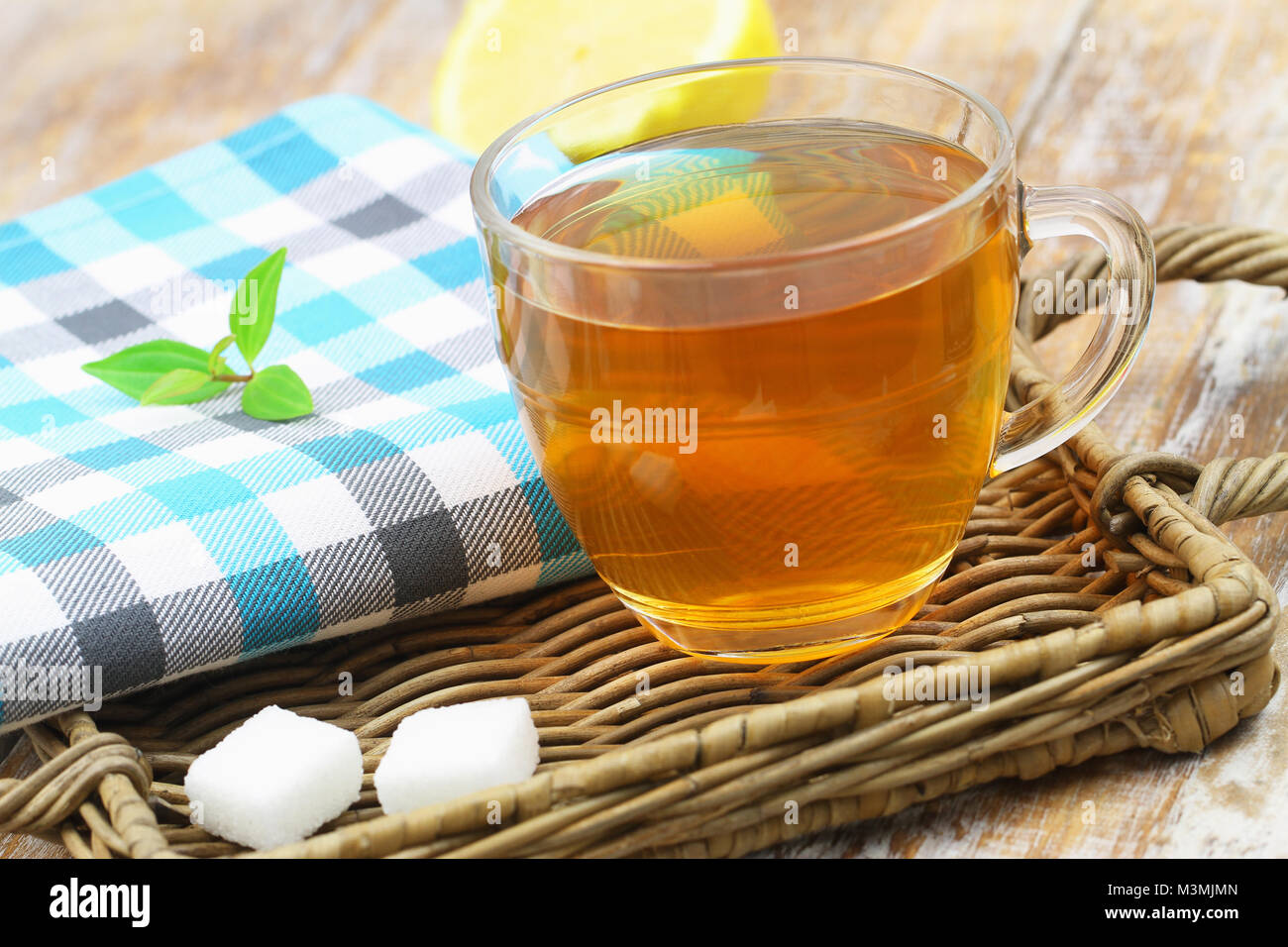 Schwarzer Tee aus transparentem Glas auf wicker Fach und zwei Würfel Zucker Stockfoto