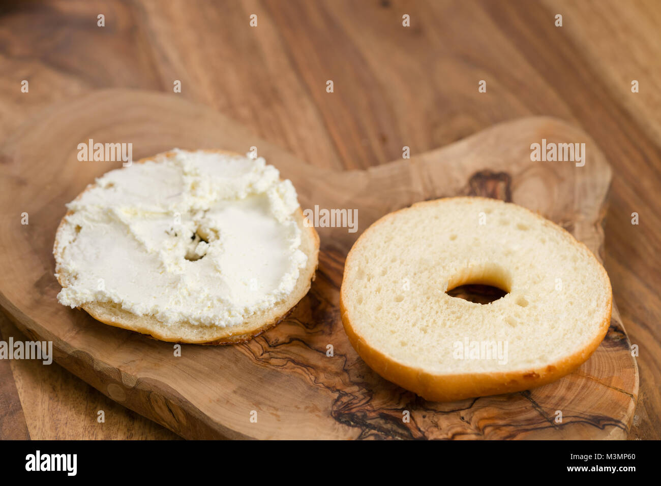 In Scheiben geschnitten Bagel mit Frischkäse auf Holz board Stockfoto