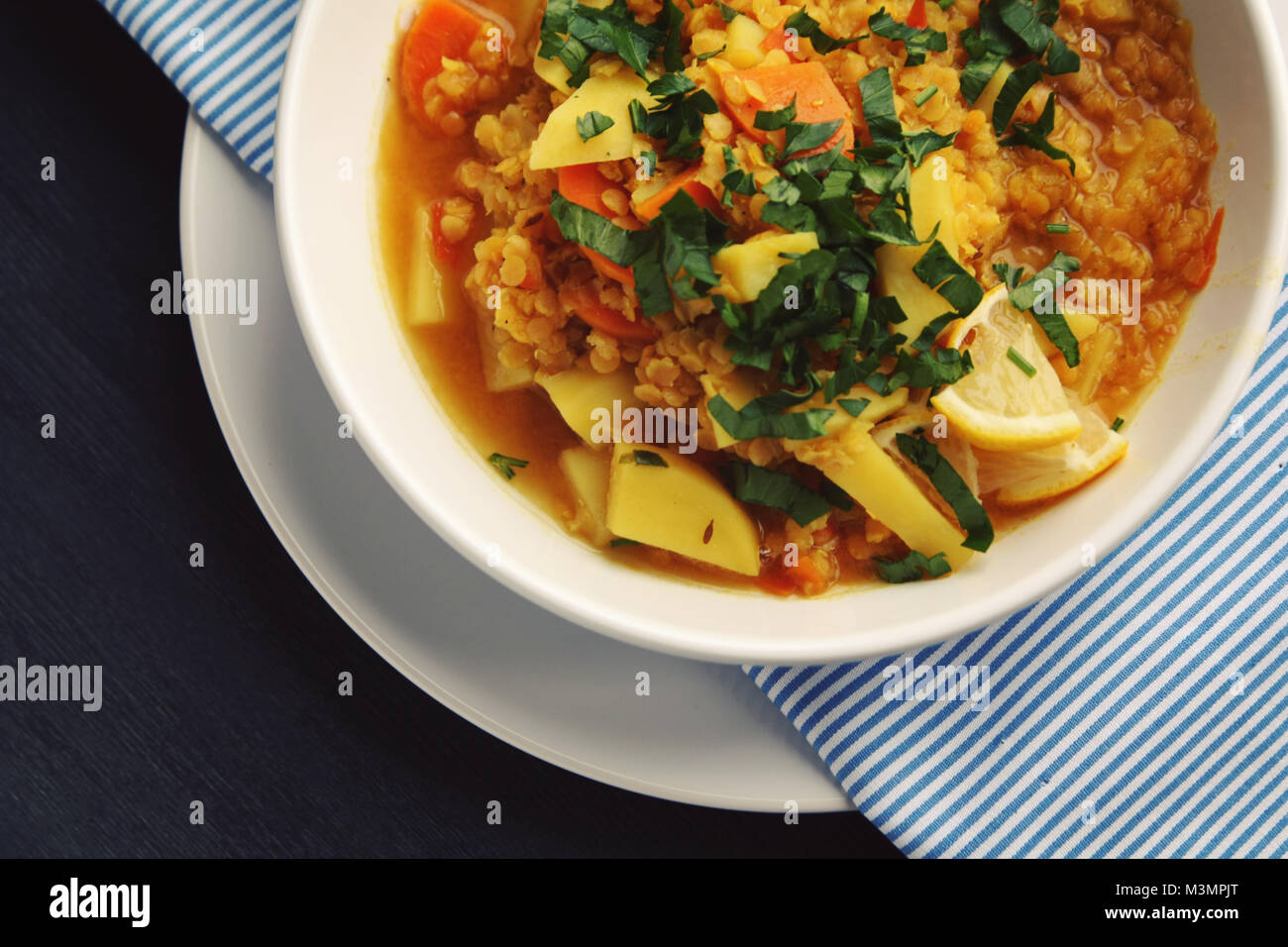 Rote Linsen Eintopf auf das runde weiße Platte. Ansicht von oben. Veganes Gericht mit Kartoffeln, Karotten und Kurkuma. Europäische Küche. Vegetarisches Mittagessen. Stockfoto