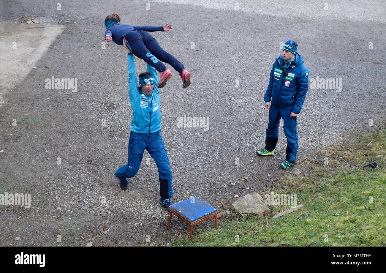 Skispringen. Ein weiblicher Wettbewerber aus dem slowenischen Team prüft die Technik von Primož Peterka die Co-Trainer geholfen wird. Stockfoto