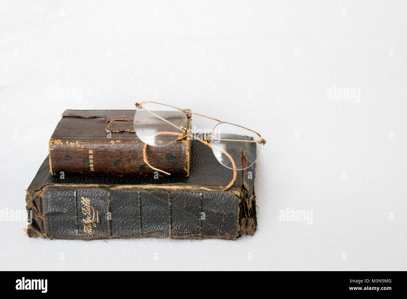 Zwei antike getragen Leder Bibeln mit antiken Randlose Gläser auf weißem Hintergrund Stockfoto