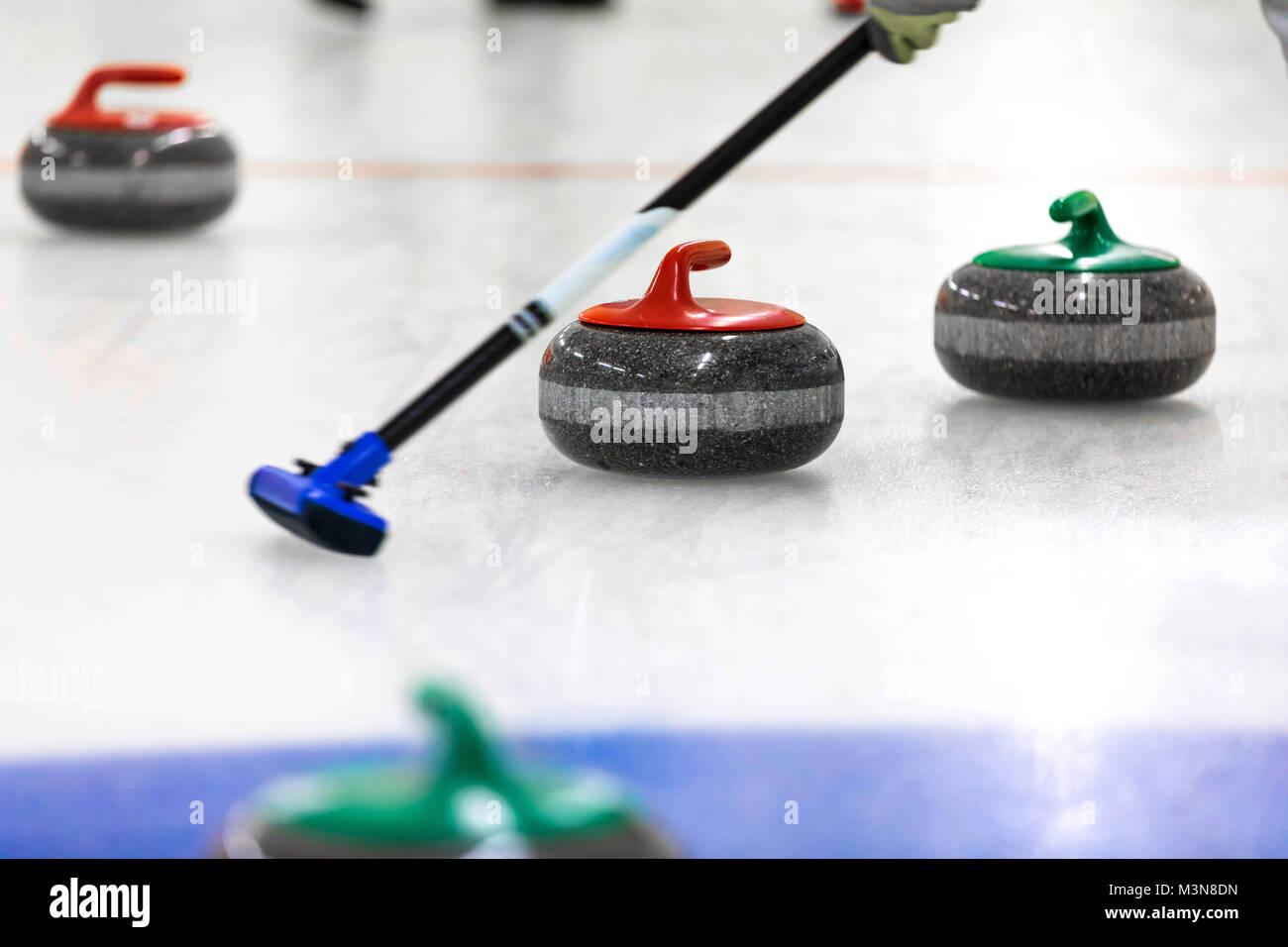 Curling Spiel - Steinen und Besen auf dem Eis Stockfoto