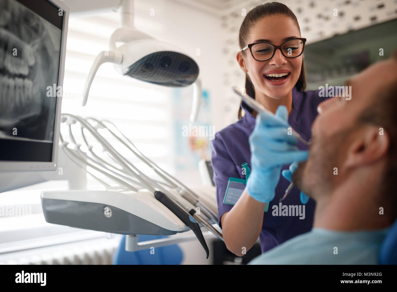 Junge lächelnde weiblichen Zahnarzt arbeiten mit männlicher Patient in der zahnmedizinischen Klinik Stockfoto