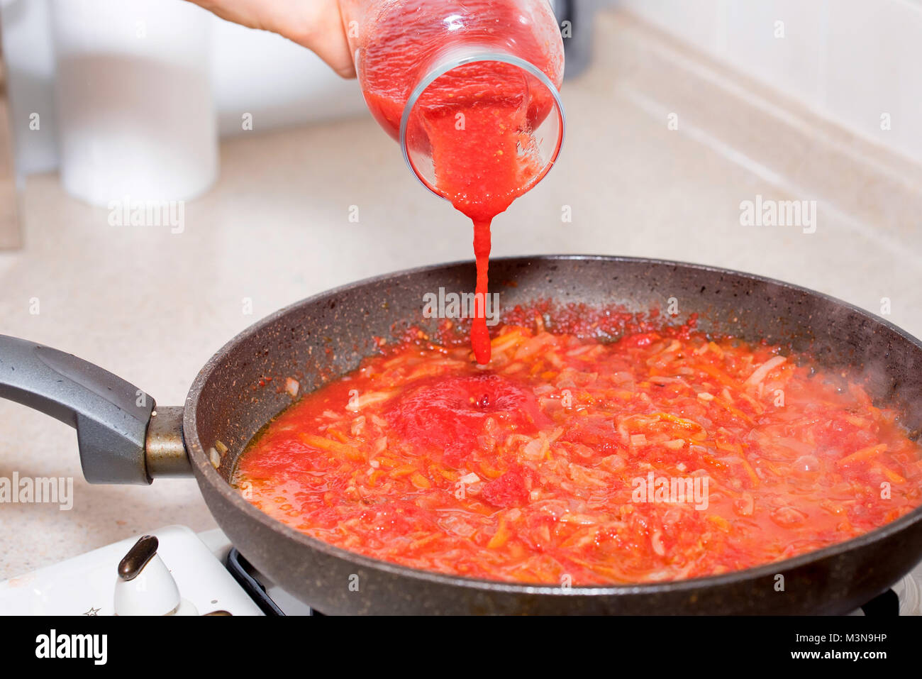 Hinzufügen von Tomatenmark zu Gemüse für Borscht Stockfoto