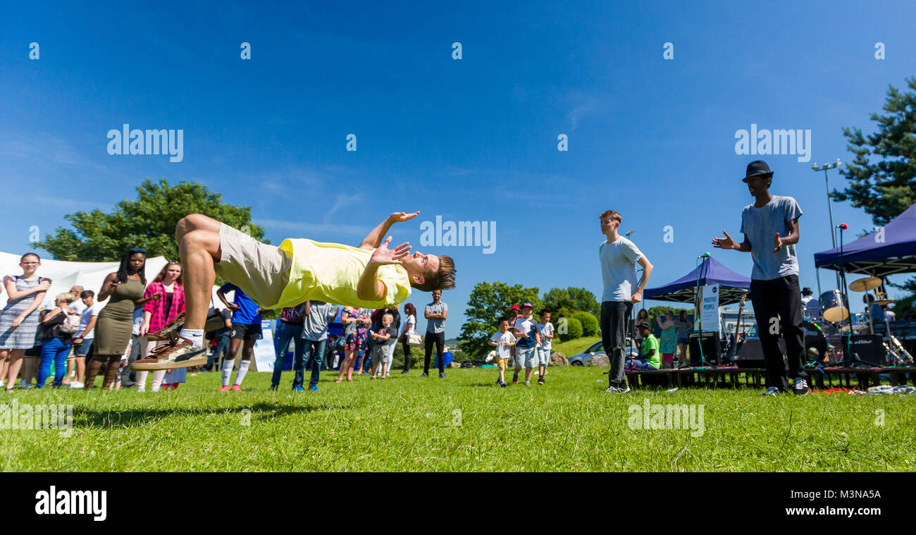 Ein Break Dancer ist mitten in der Luft ausgesetzt, wie er einen Rückwärtssalto während Zuschauer in Erstaunen führt Stockfoto