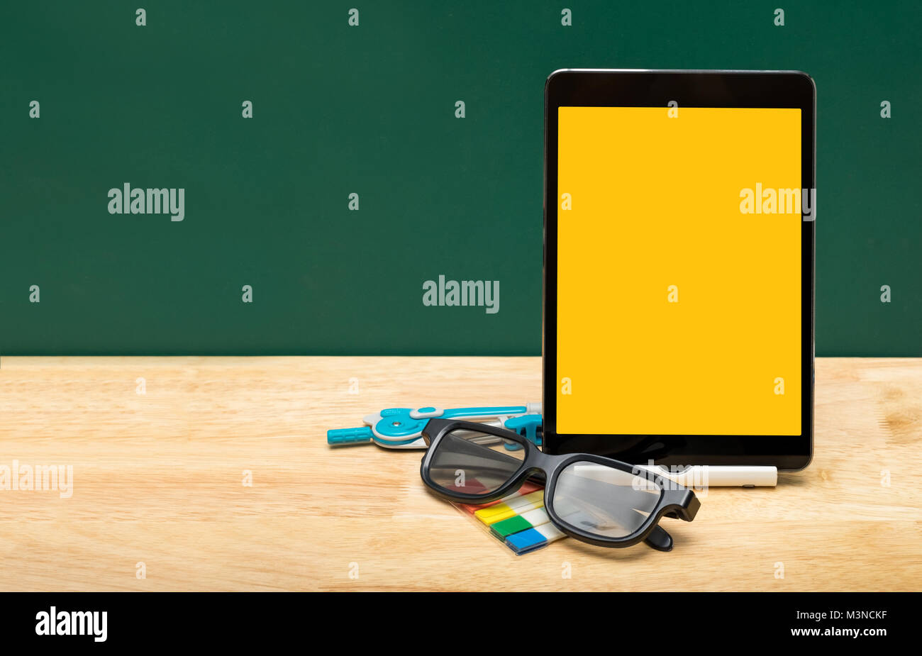 Leere gelbe Tablet mit Brillen, Bleistift auf Holz Tisch mit grünen Tafel, Bildung Konzept. e-learning. freistellungspfad Bildschirm Stockfoto