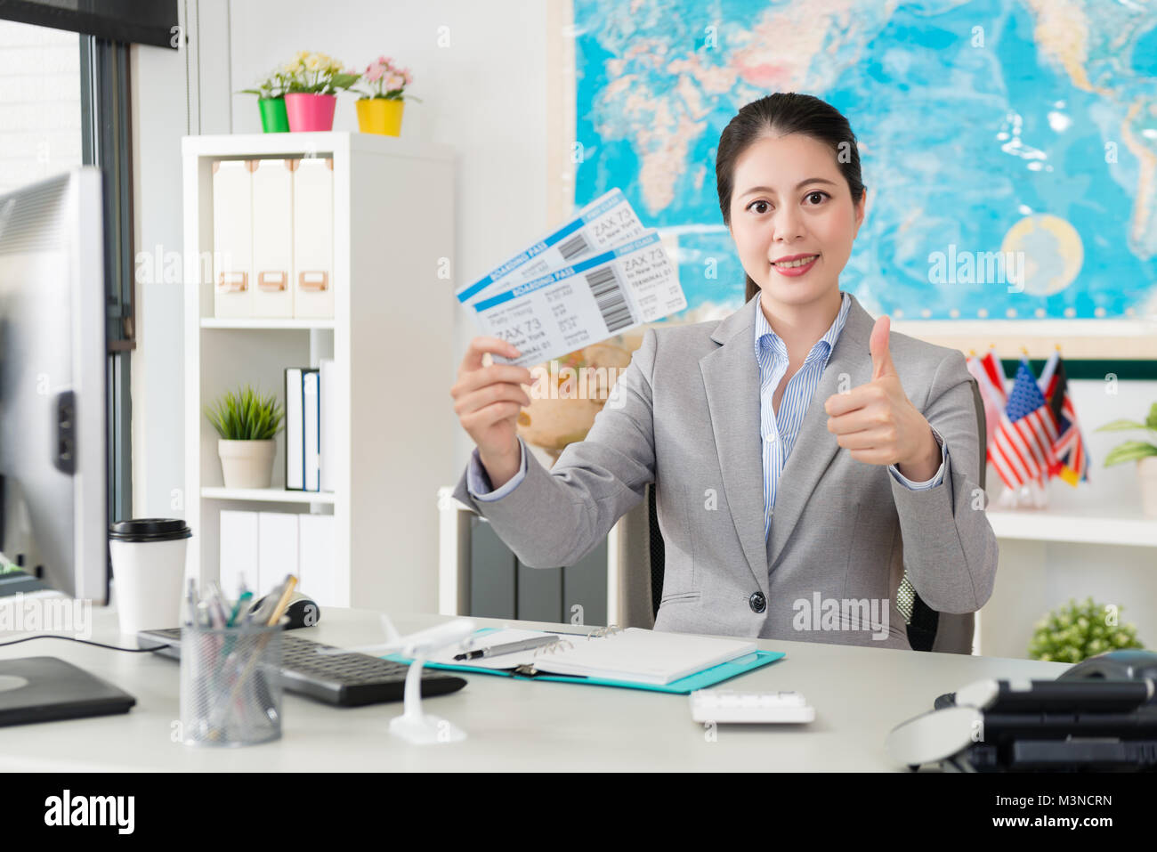 Professionelle junge weibliche Reisebüro Büroangestellter holding Airline Tickets zu Kamera Gesicht und zeigt "Daumen hoch" Geste. Stockfoto