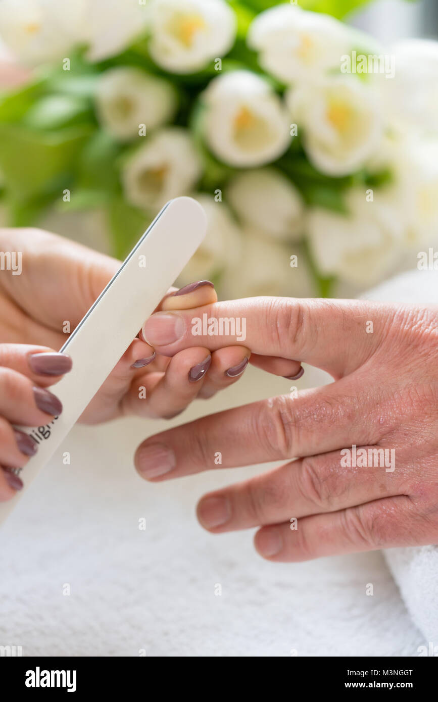 Nahaufnahme der Hand eines qualifizierten Maniküre Feilen der Nägel, einer jungen Frau mit einem weißen Puffer in einem trendy Nail Salon Stockfoto