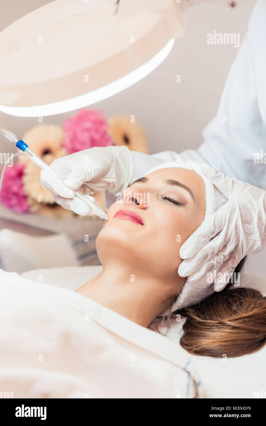 Schöne Frau Entspannung während nicht-invasive Gesichtsbehandlung für Verjüngung in ein modernes Beauty Center mit innovativer Ausstattung Stockfoto