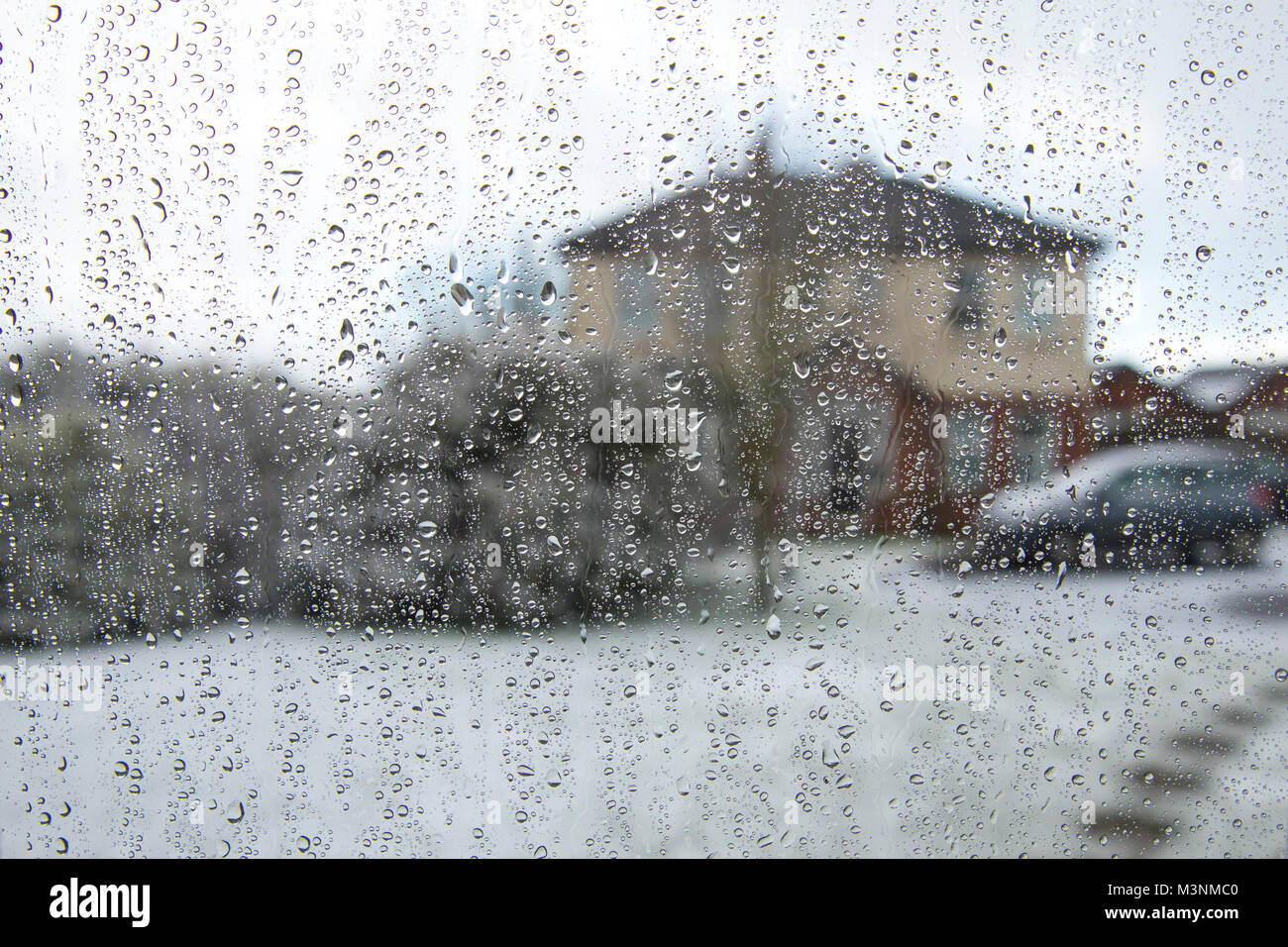 Regen fällt auf Fenster mit unscharfen Hintergrund und Schnee auf dem Boden Stockfoto
