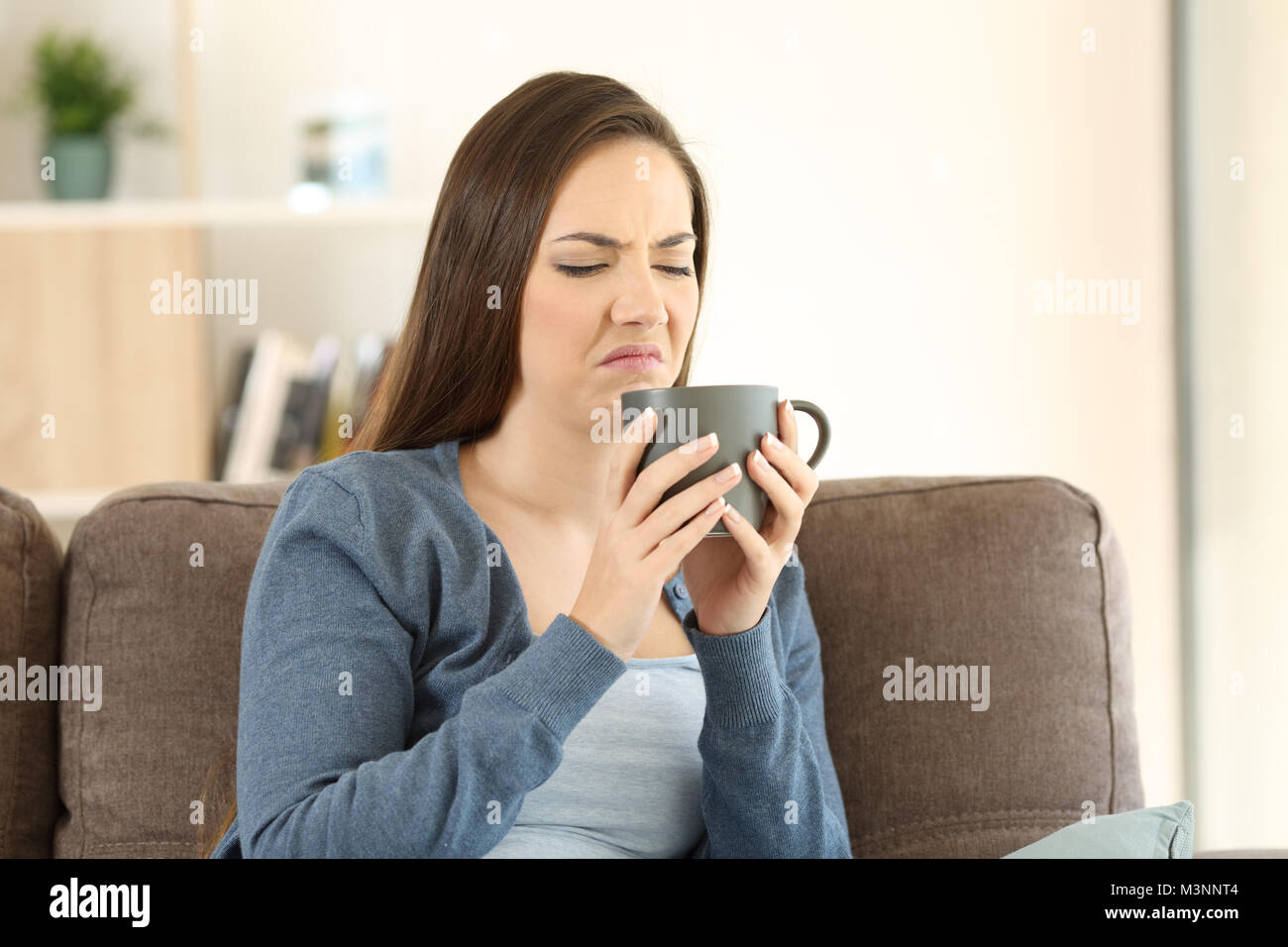 Frau leiden Trinken schlechter Geschmack auf einer Couch im Wohnzimmer zu Hause sitzen Stockfoto