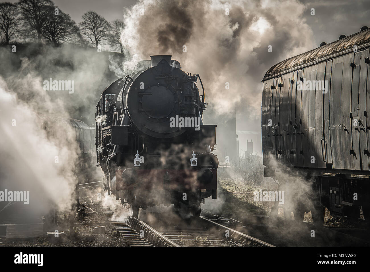 Einen frühen Morgen beleuchtete Foto einer Dampfeisenbahn rauchen und Dampf atmosphärische Bild Stockfoto