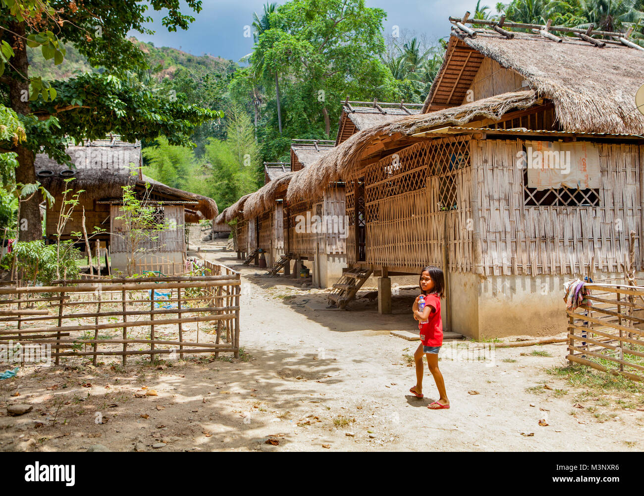 Eine junge philippinische einheimische Mangyanen Mädchen geht zu ihrem Haus im Dorf Talipanan mit Ihrer Wasserflasche. Oriental Mindoro, Philippinen. Stockfoto