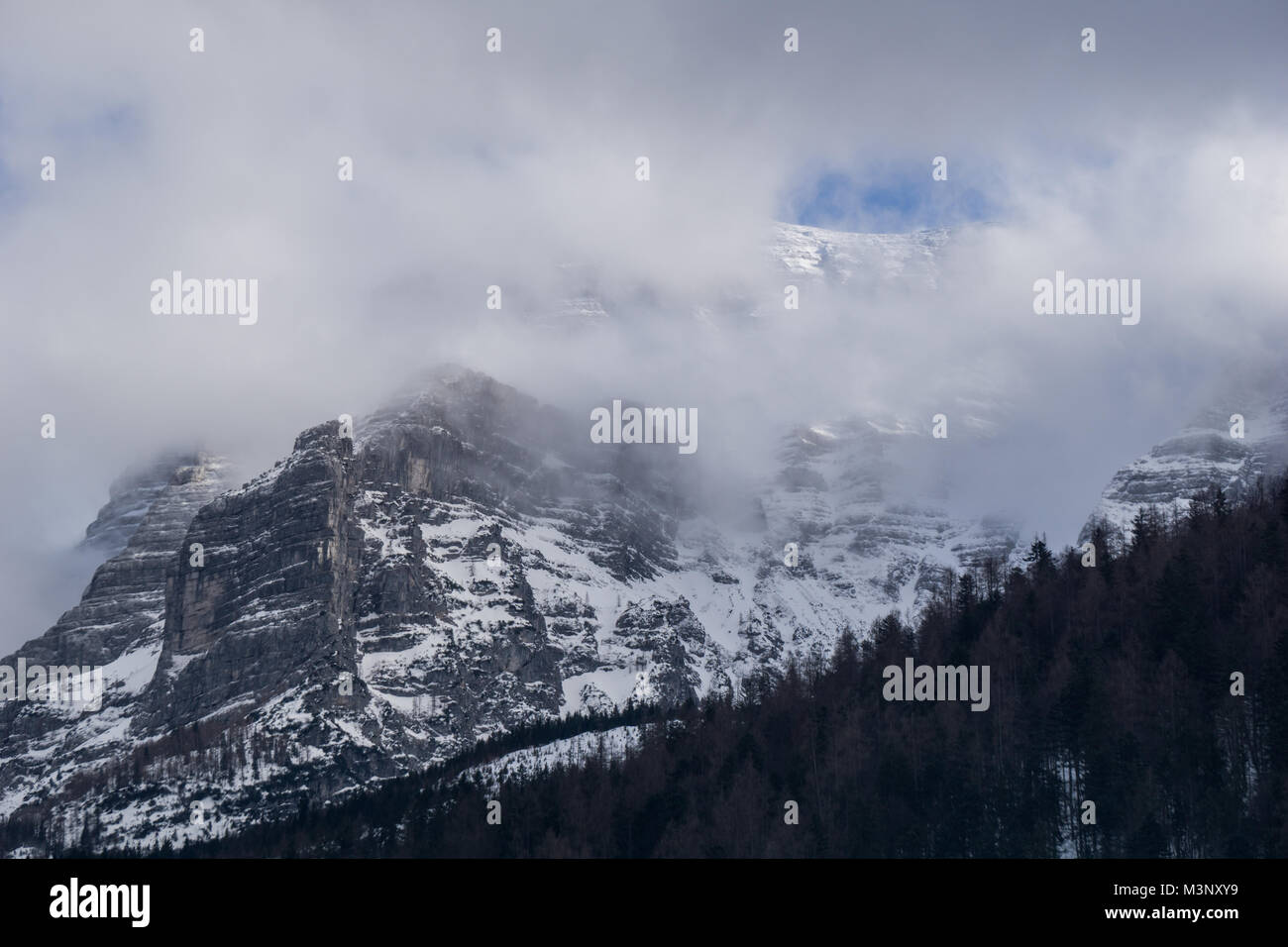 Ein kleines Fenster in den Wolken zeigt den Berg im Schnee und blauem Himmel bedeckt Stockfoto