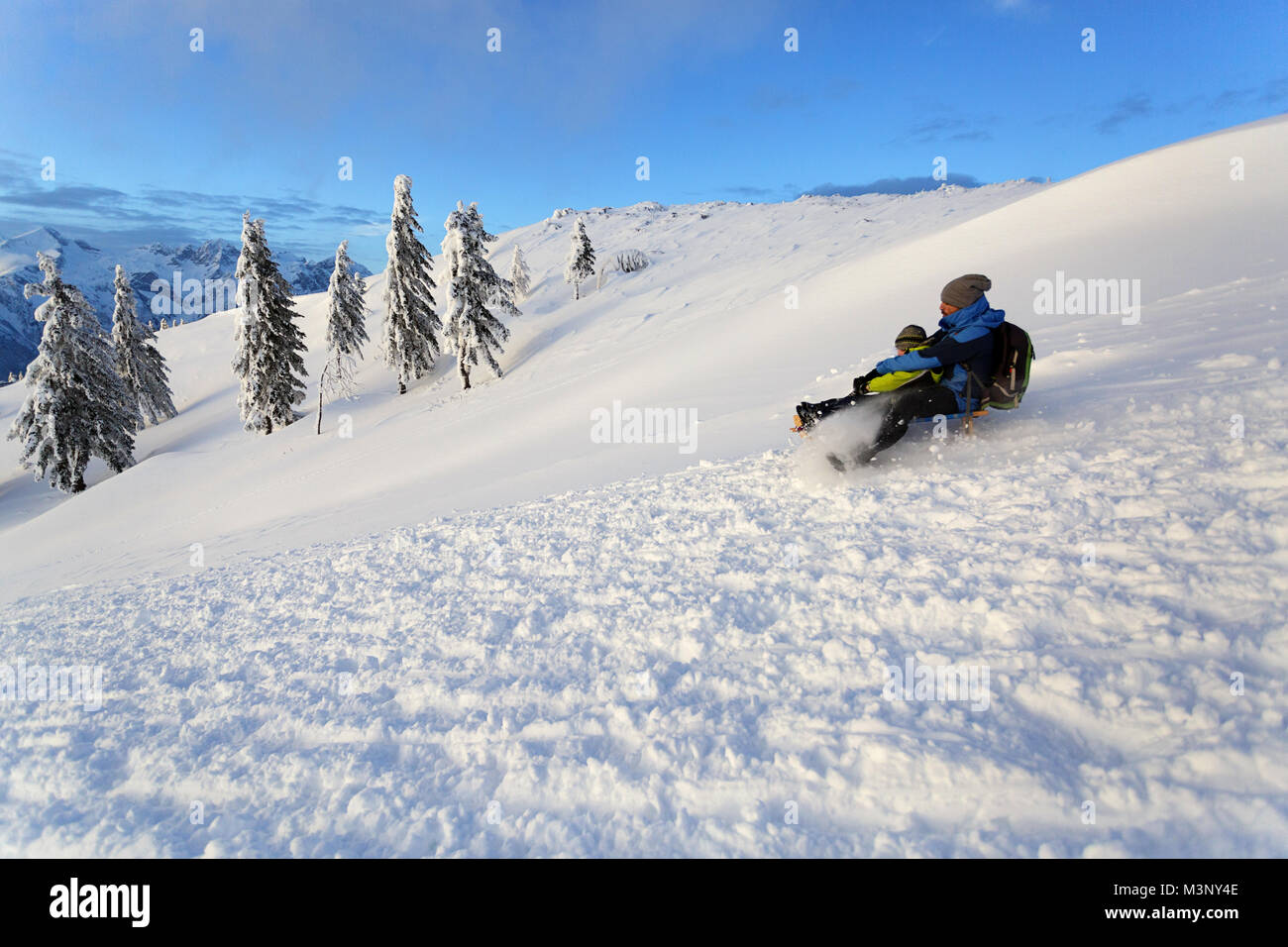 Vater und Sohn Rodeln von Schnee bedeckten Berg mit super Aussicht, winter Wanderland, Winter Genuss, Velika Planina, Slowenien. Stockfoto