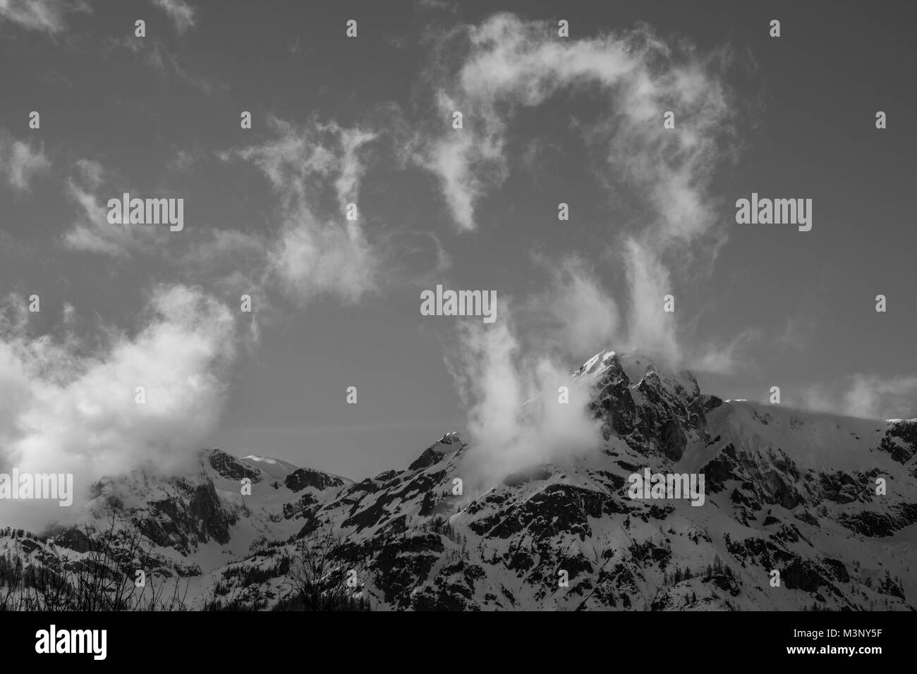 Schwarz-weiß Bild von Wolken durch hohe Berge an einem kalten Wintertag gestört wird, Stockfoto