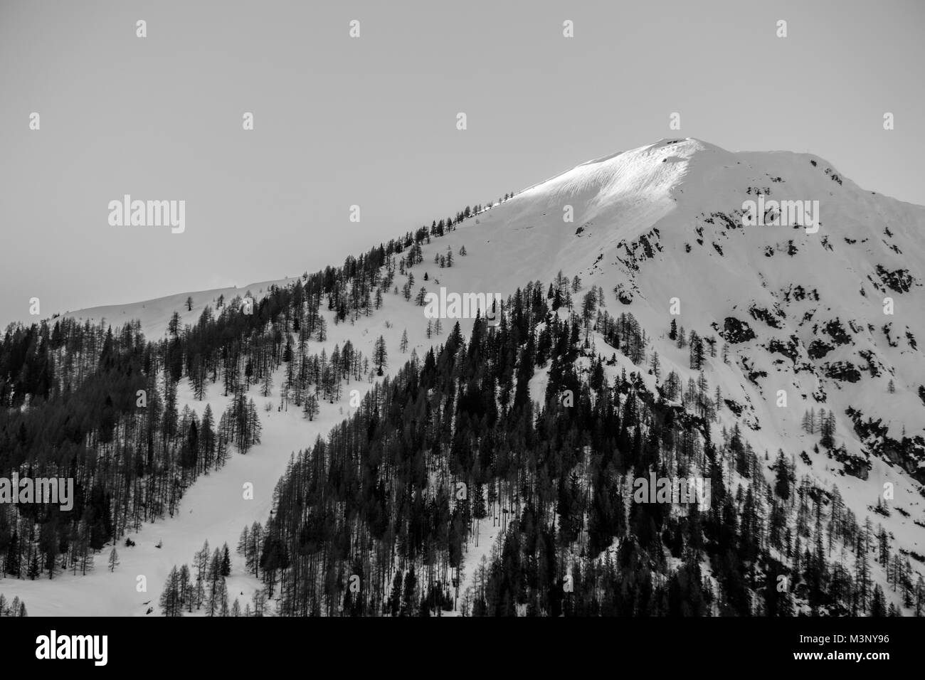 Schwarze und weiße geschossen von den letzten Strahlen der Sonne schlagen die schneebedeckten Gipfel eines Berges in den Alpen Stockfoto