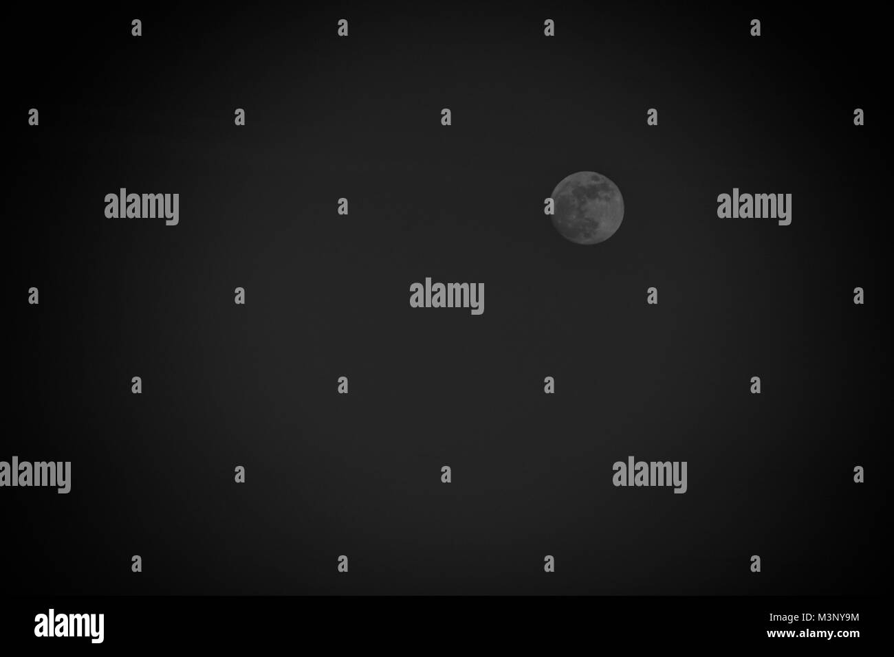 Schwach beleuchteten Mond auf einem schwarzen Hintergrund verblasst Stockfoto