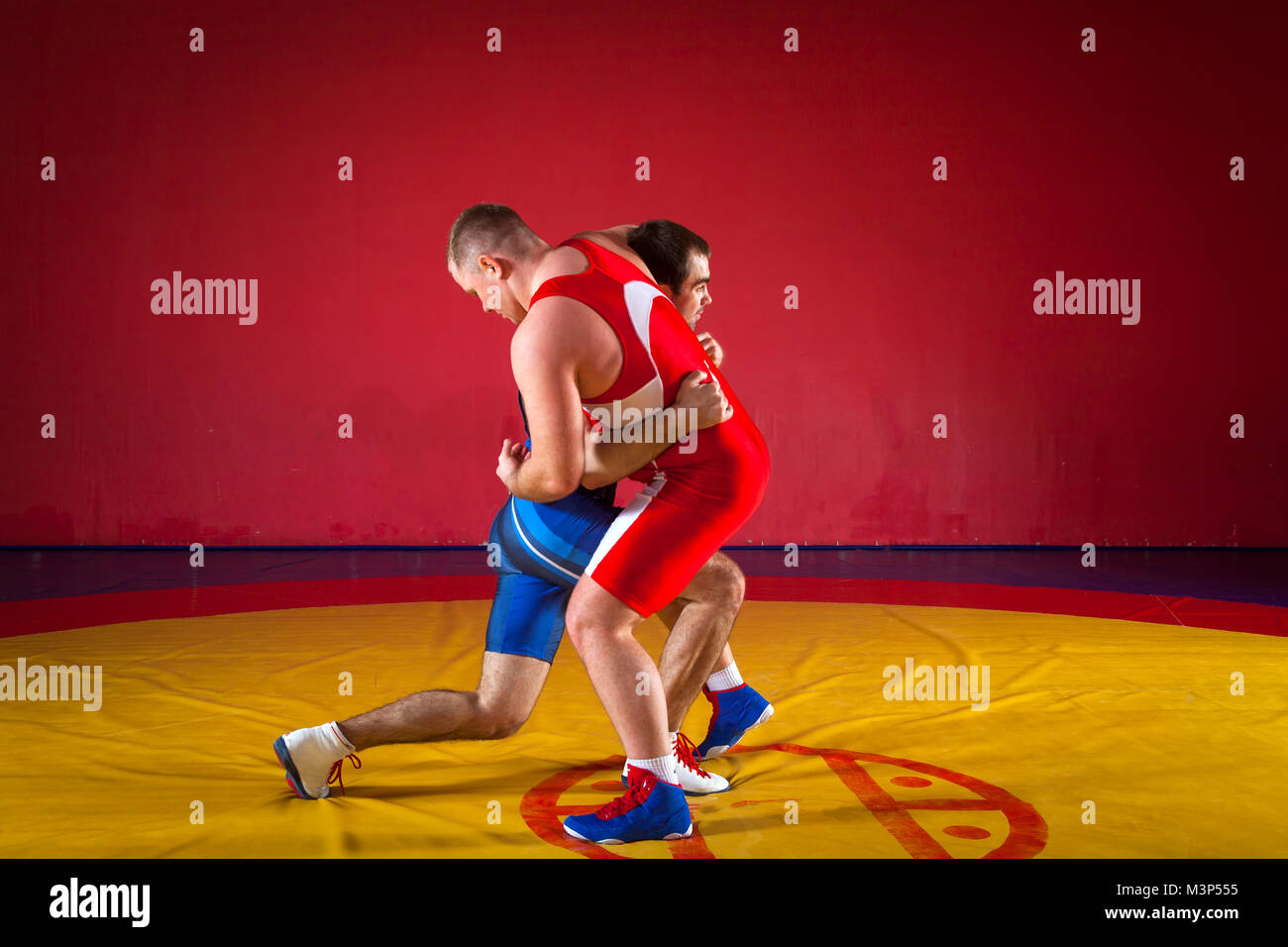 Zwei starke Ringer in Blau und Rot wrestling Strumpfhosen sind wrestlng und  Tun auf einer gelben wrestling Teppich in der Turnhalle auseinander  Stockfotografie - Alamy