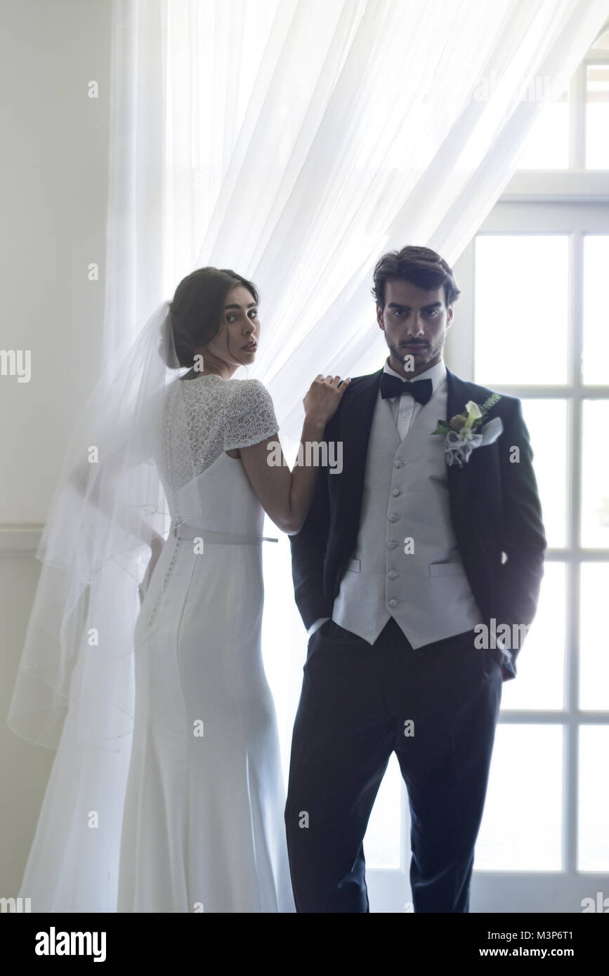 Schöne dunkelhaarige Braut und Bräutigam auf eine gestaltete Hochzeitstag - traditionelles weißes Kleid/schwarzen Anzug - Art déco-Stil mit hellen, sonnigen Tag Stockfoto