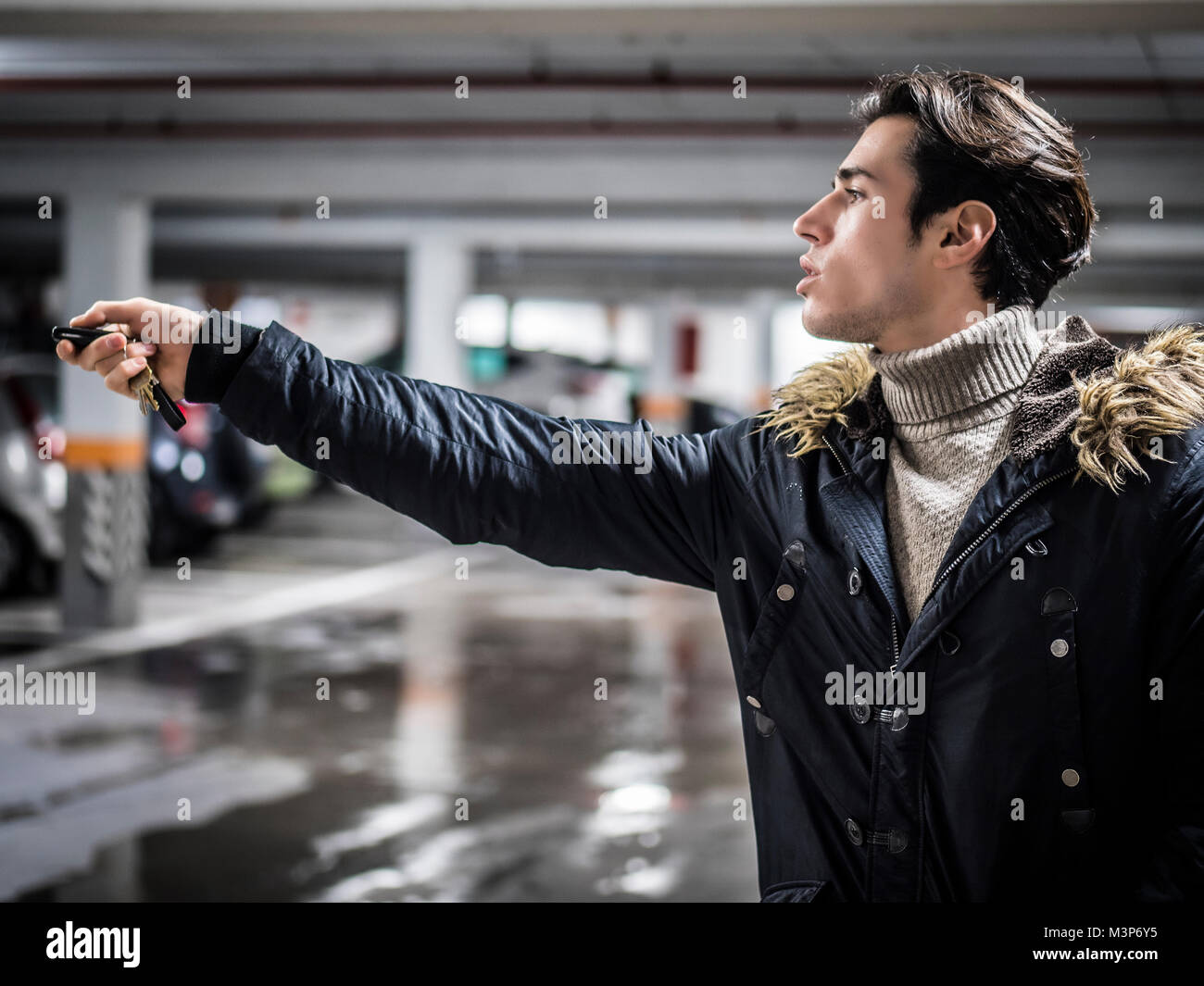 Junge trendige Mann in der Oberbekleidung auf Parkplatz mit alarm Fernbedienung. Stockfoto