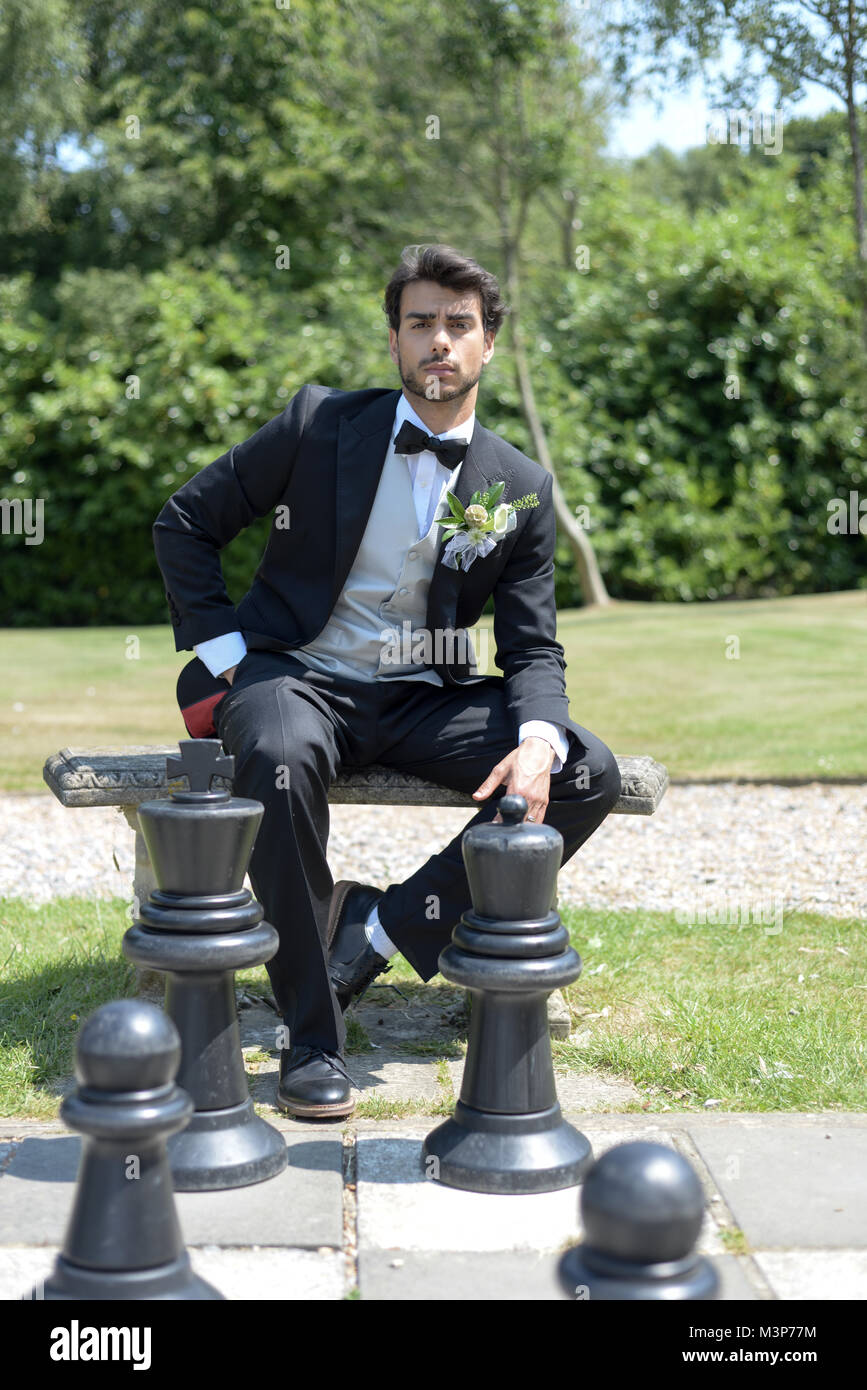 Porträt einer hübschen dunkelhaarigen jungen Mann Hochzeit Kleidung auf einem hellen, sonnigen Tag, blickt er zuversichtlich und fröhlich Stockfoto