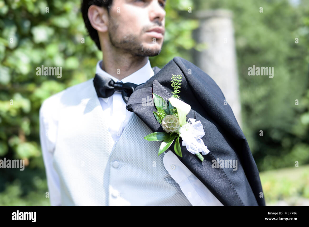 Porträt einer hübschen dunkelhaarigen jungen Mann Hochzeit Kleidung auf einem hellen, sonnigen Tag, blickt er zuversichtlich und fröhlich Stockfoto