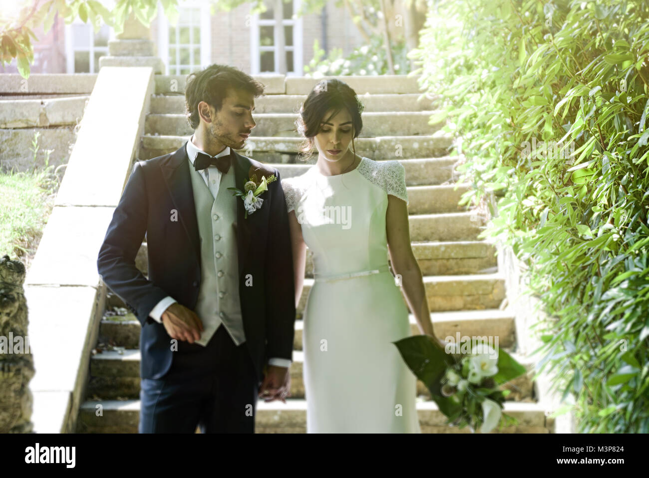 Schöne dunkelhaarige Braut und Bräutigam auf eine gestaltete Hochzeitstag - traditionelles weißes Kleid/schwarzen Anzug - Art déco-Stil mit hellen, sonnigen Tag Stockfoto