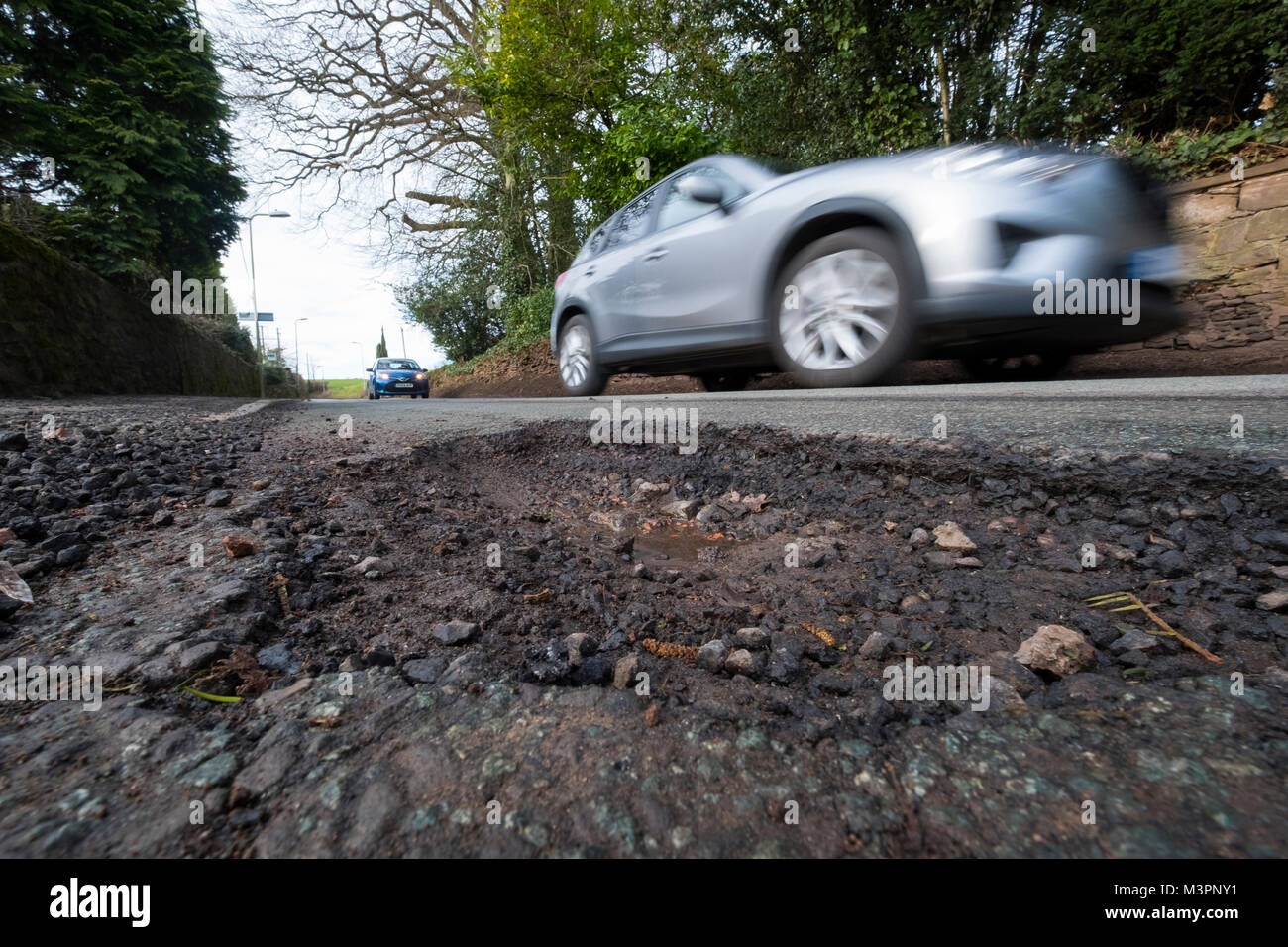Autos passieren ein tiefes Schlagloch in Shifnal, Shropshire, wie Straßenzustand im gesamten Bereich verschlechtern. Stockfoto