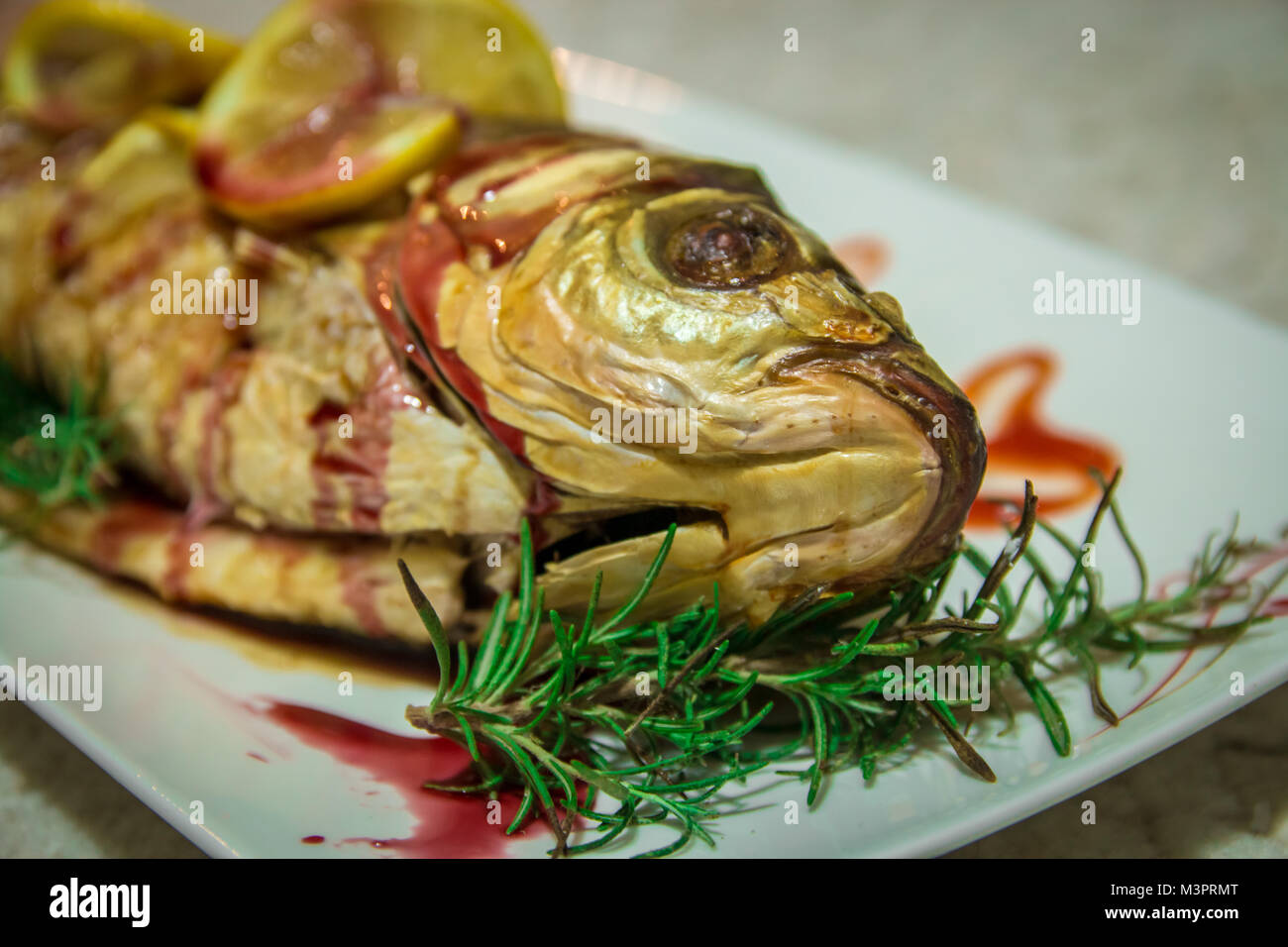 Fisch mit Zitrone Keile und eine grüne Rosmarin. Geringe Tiefenschärfe. Stockfoto