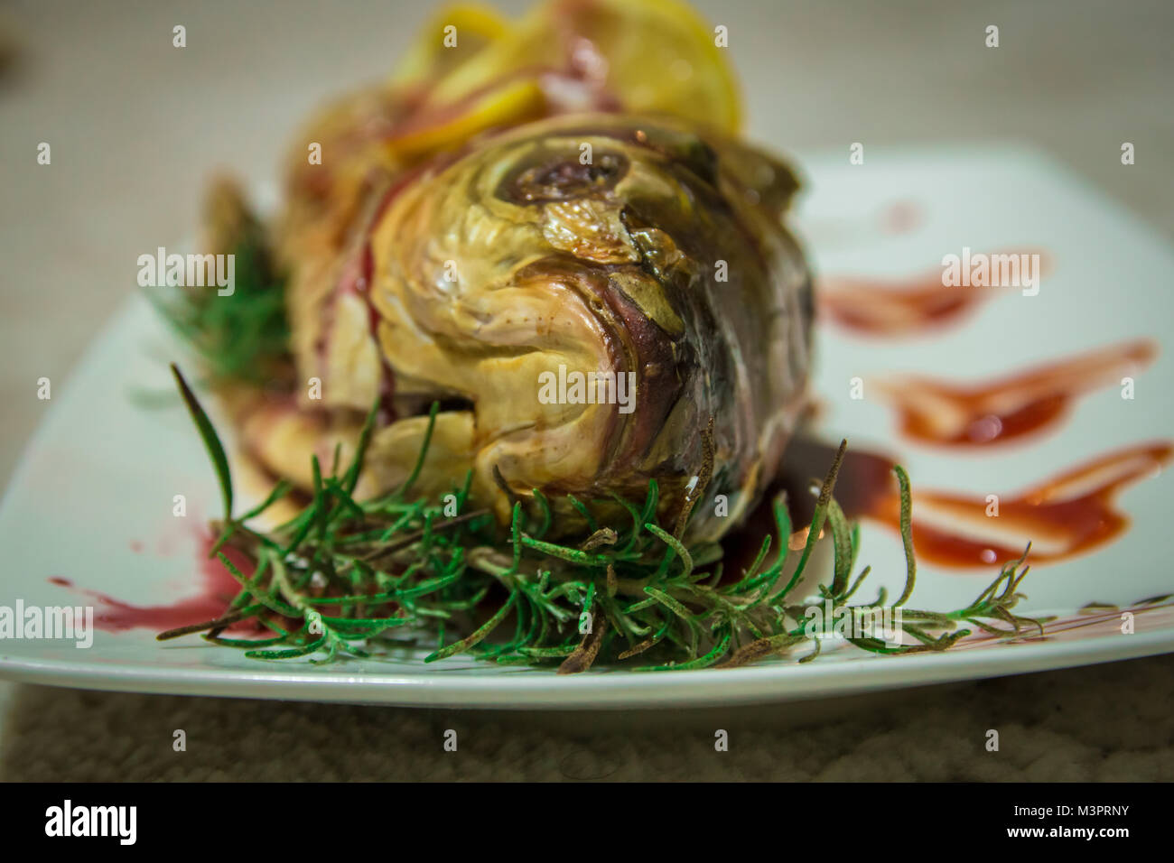 Fisch mit Zitrone Keile und eine grüne Rosmarin. Geringe Tiefenschärfe. Stockfoto