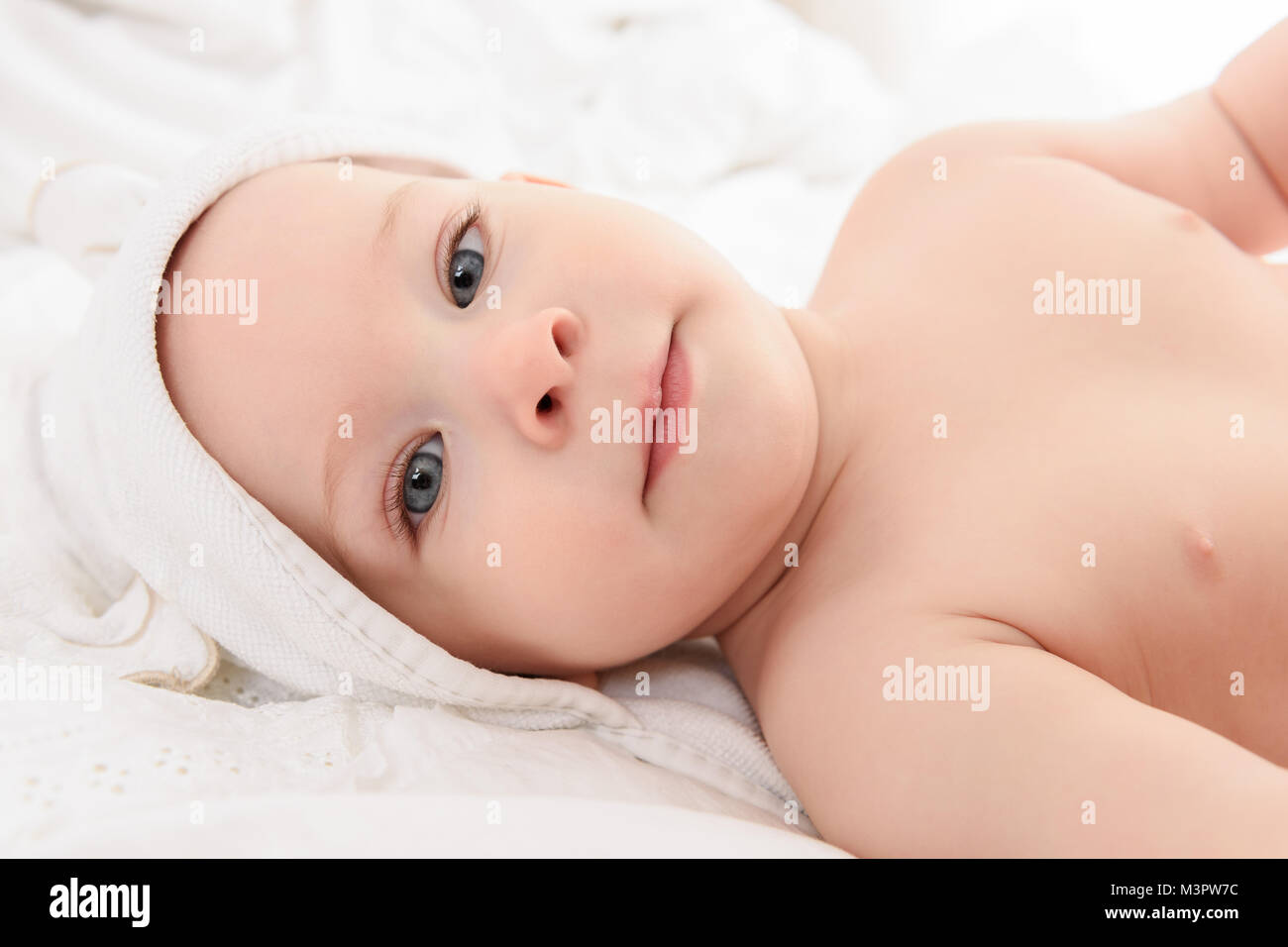 Happy Baby Boy tragen Kapuzentuch liegen auf einem Bett nach dem Bad oder  Dusche. Junges Kind mit blauen Augen in die Kamera schauen Stockfotografie  - Alamy