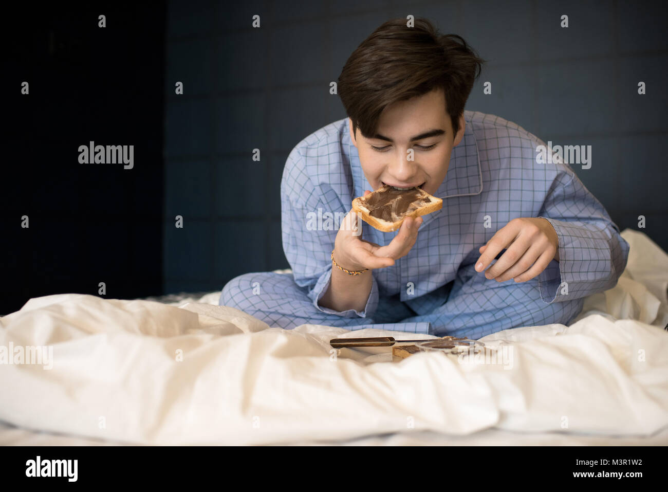 Junge Essen Crunchy Toast im Bett Stockfoto