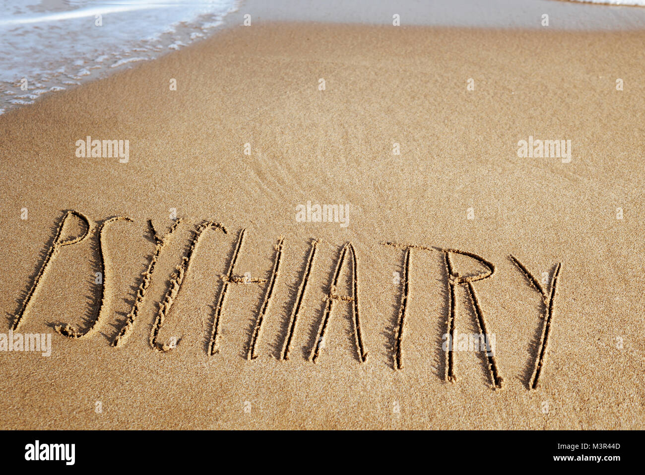 Das Wort Psychiatrie in den Sand geschrieben, ein Strand mit Meer Schaum auf der linken Seite und leeren Raum auf der Oberseite Stockfoto