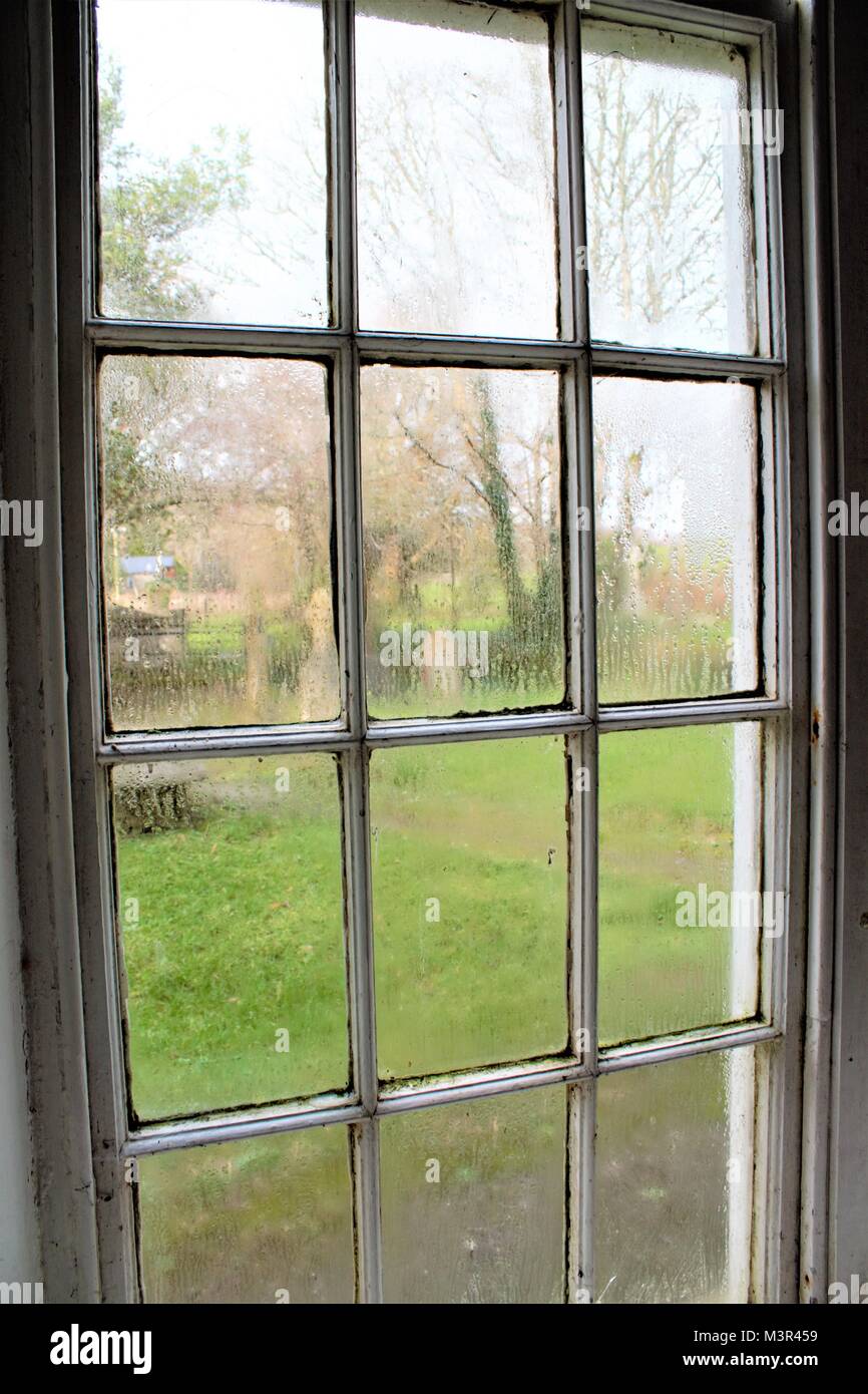 Kondensation auf einer Kirche Fenster mit Blick auf den Friedhof. Stockfoto