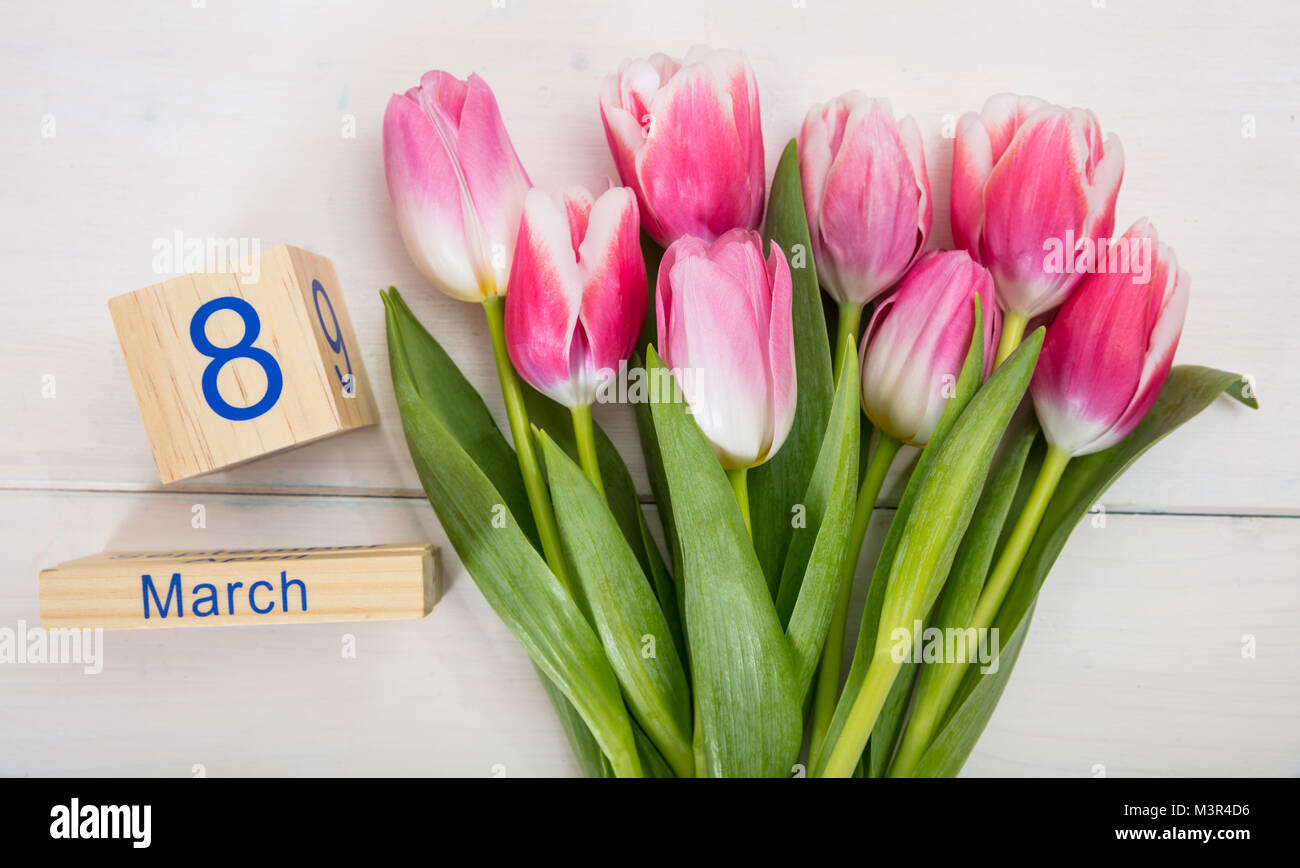 Tag der Frauen Konzept. Rosa Tulpen Bouquet, der 8. März Datum auf weißem Holz- Hintergrund Stockfoto